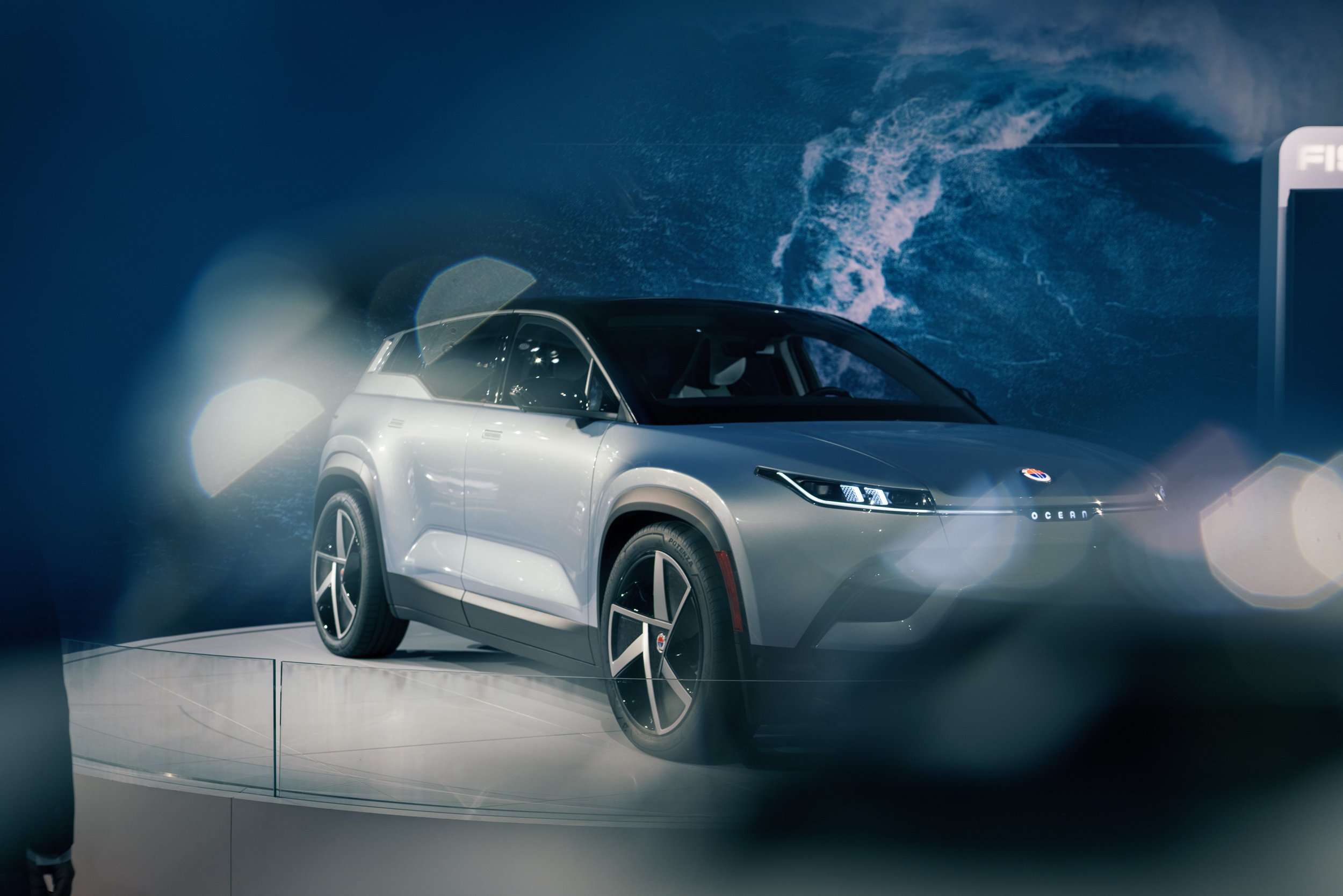 Electric SUV on display with ocean-themed background