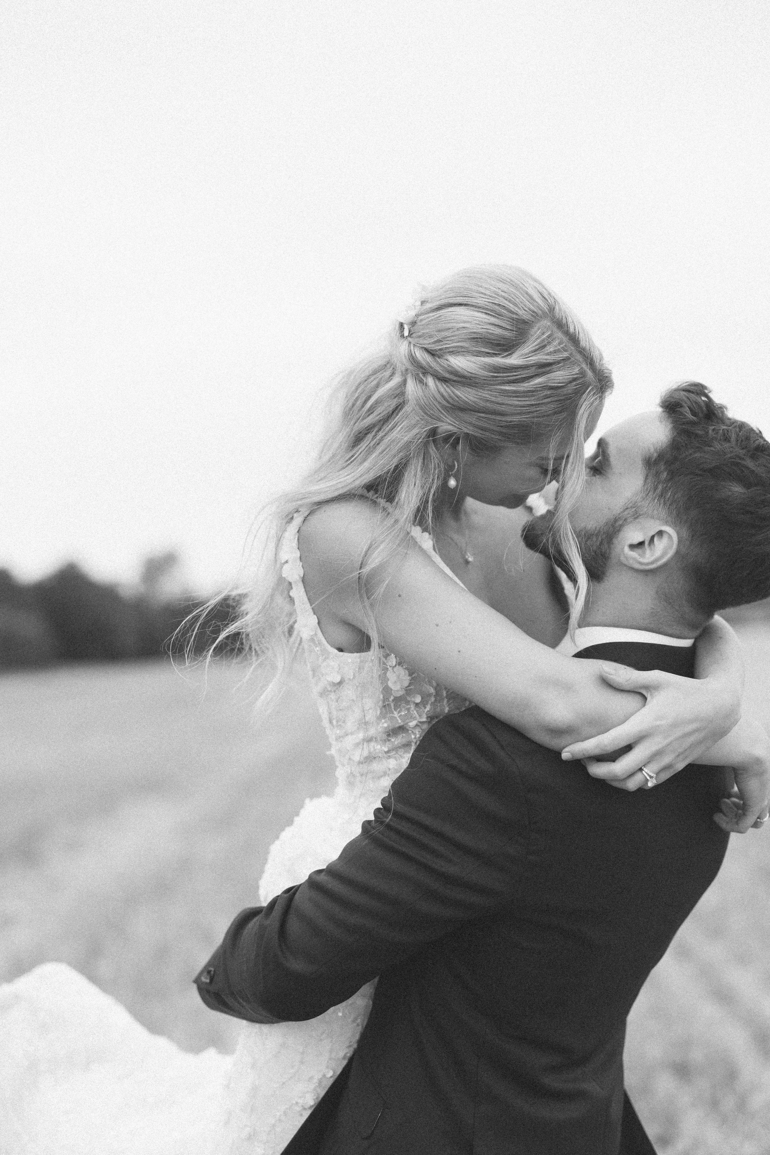 A bride and groom kiss in the wheat fields at their wedding at Lains Barn