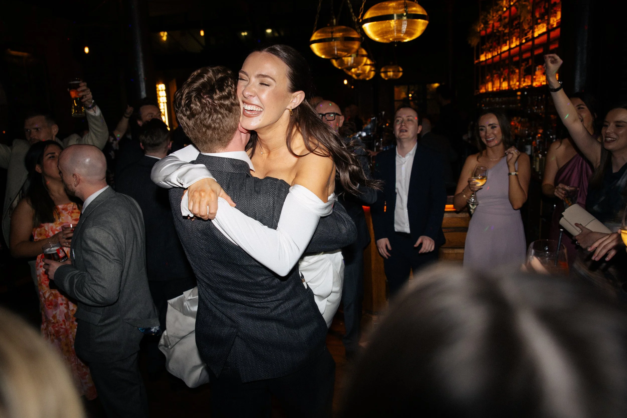 A groom spins his bride in the air at the party after their wedding at Harrild and Sons 