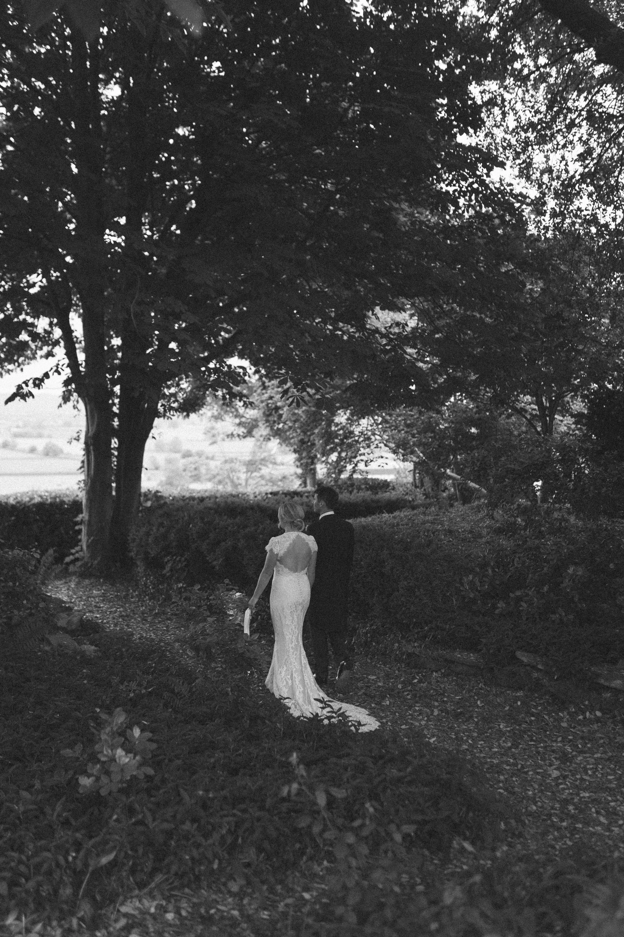 A bride and groom stroll through the trees during the reception at their wedding