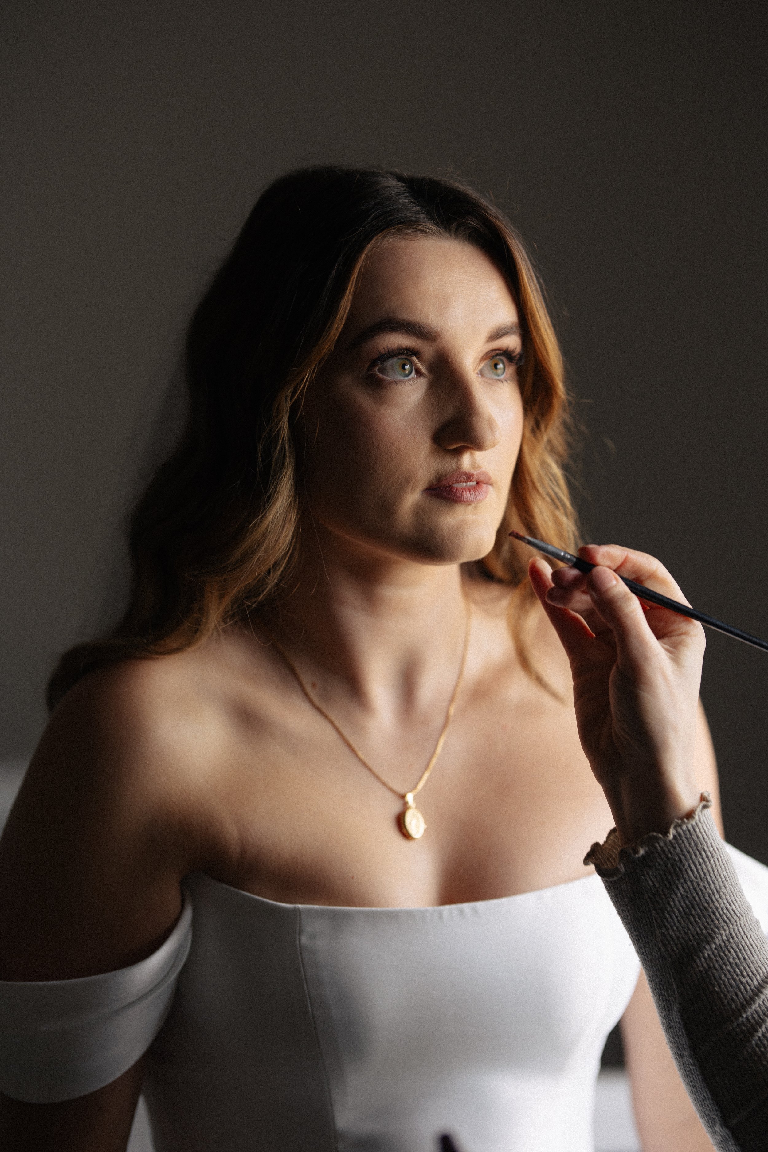 A bride has the finishing touches of her make up applied before her wedding at Alrewas Hayes