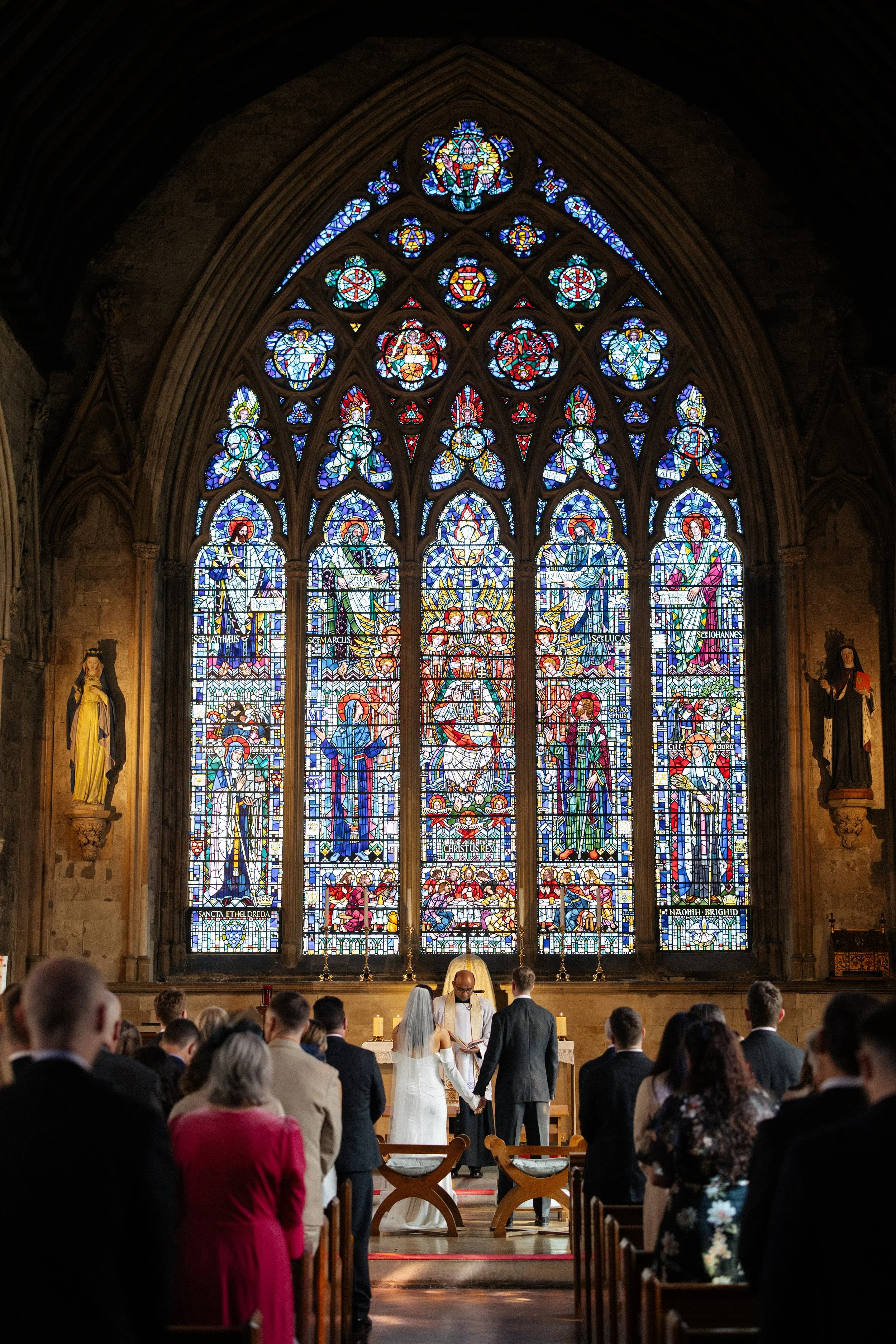 A bride and groom stand at the alter at St Ethelreda's Church in London