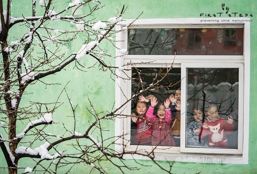 Children look through the window at the Yangji Daycare in Wonsan