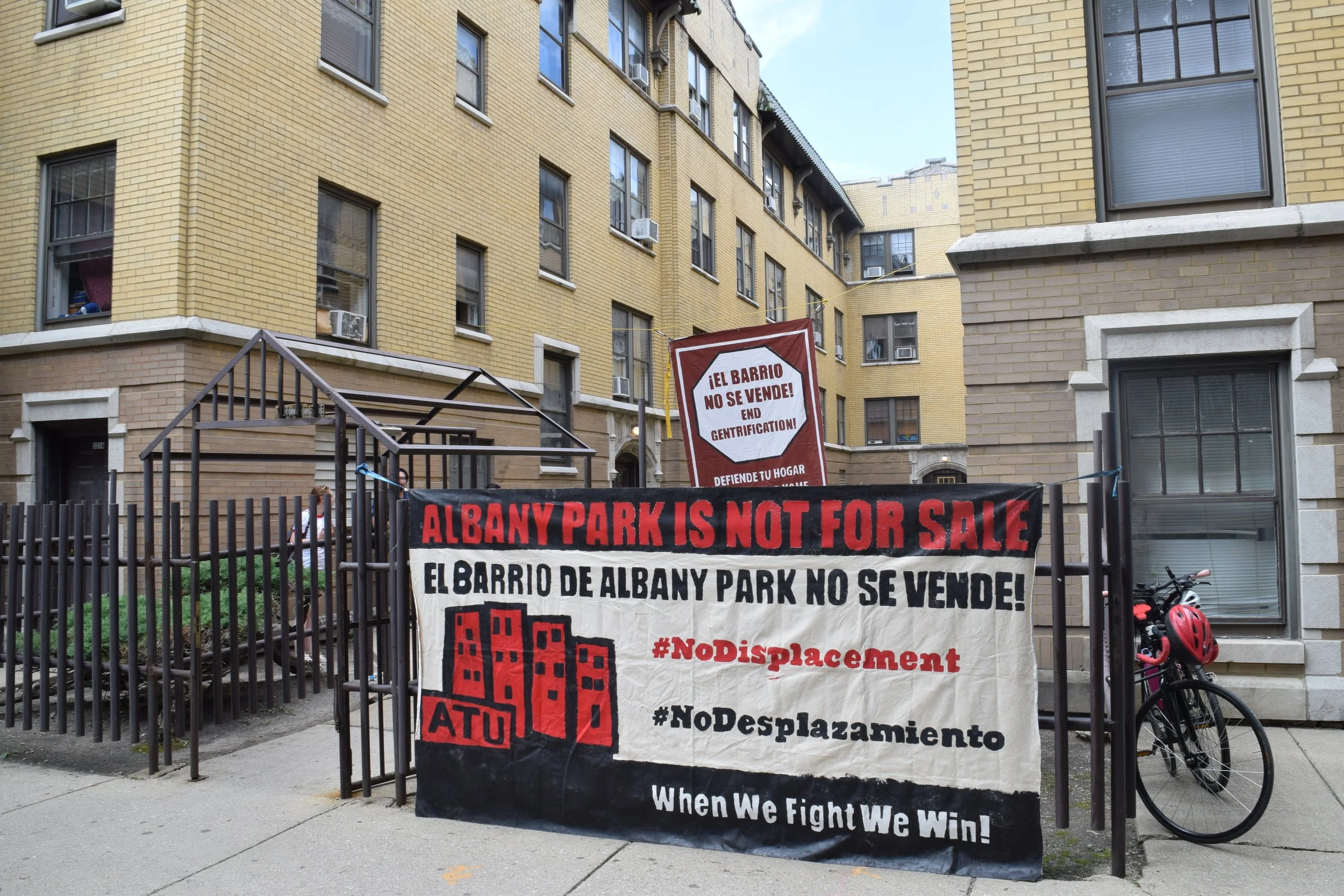 A banner outside a many-unit building reads " Albany Park is Not for Sale" "El Barrio de Albany Park No Se Vende"