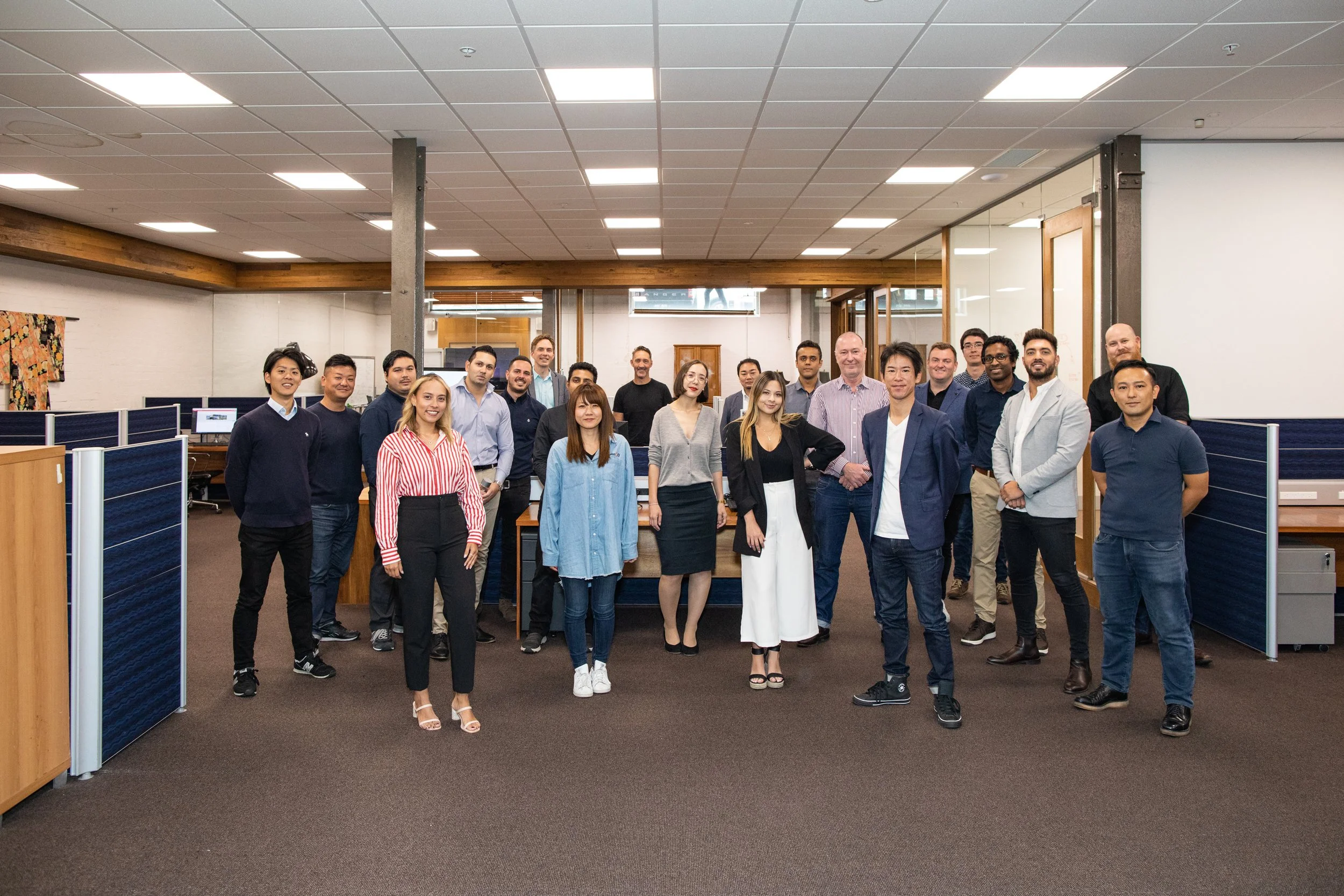 A diverse group of young professionals posing for a photo in an office space.