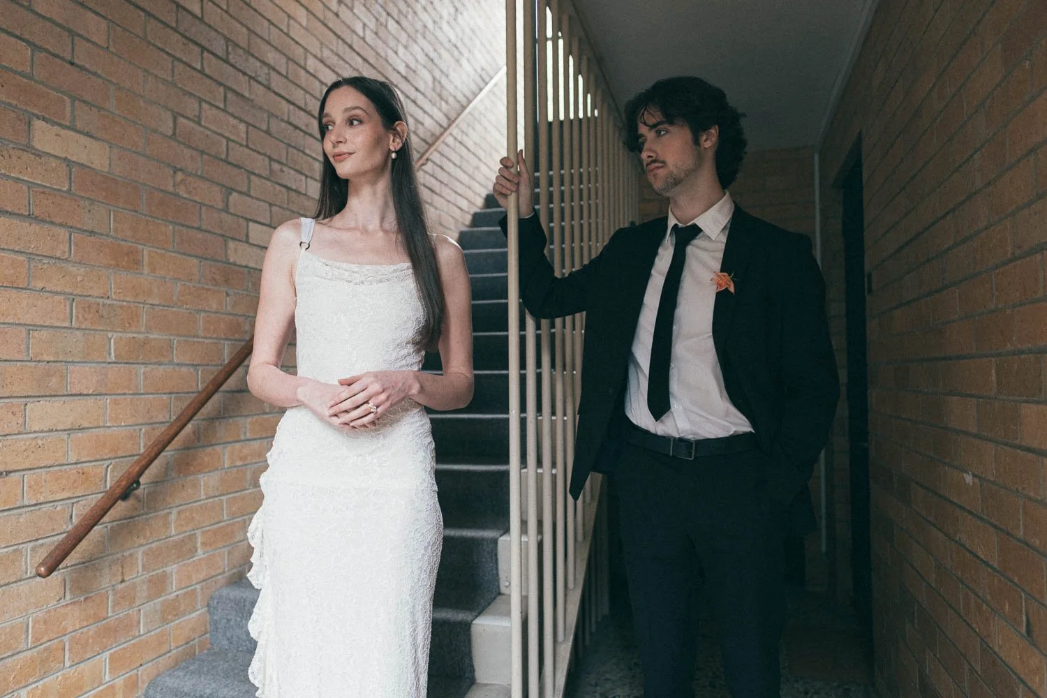 , BRIDE AND GROOM CASUALLY POSING AT AN APARTMENT NEXT TO STAIRCASES WITH A ONE POINT PERSPECTIVE