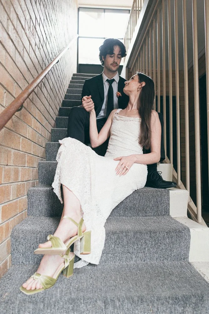 , BRIDE AND GROOM CASUALLY POSING AT AN APARTMENT NEXT TO STAIRCASES WITH A ONE POINT PERSPECTIVE