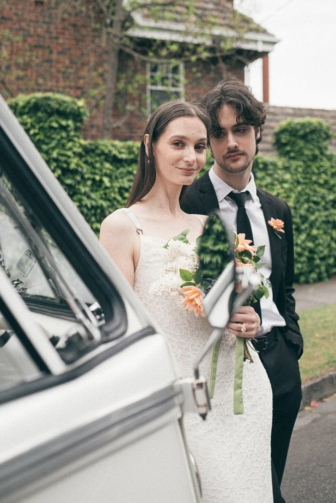 MELBOURNE  EDITORIAL WEDDING PHOTOGRAPHY, BRIDE AND GROOM POSING NEXT TO A OLD SCHOOL VW KOMBI VAN, BOTH LOOKING INTO THE LENS