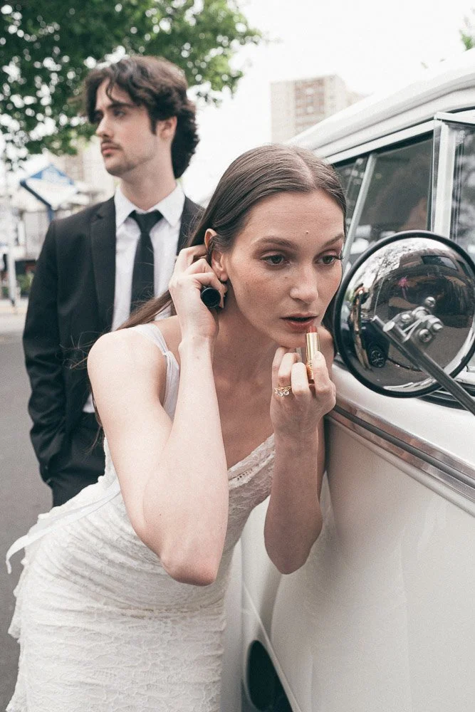 MELBOURNE  EDITORIAL WEDDING PHOTOGRAPHY, BRIDE AND GROOM POSING NEXT TO A OLD SCHOOL VW KOMBI VAN, INSIDE THE VAN HAVING A CHAMPAGNE IN CLASSIC FLUTES, BRIDE FIXING HER LIPSTICK IN THE KOMBI MIRROR