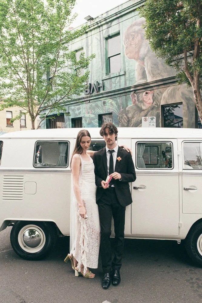 MELBOURNE  EDITORIAL WEDDING PHOTOGRAPHY, BRIDE AND GROOM POSING NEXT TO A OLD SCHOOL VW KOMBI VAN IN FRONT OF HUGE GRAFITTI