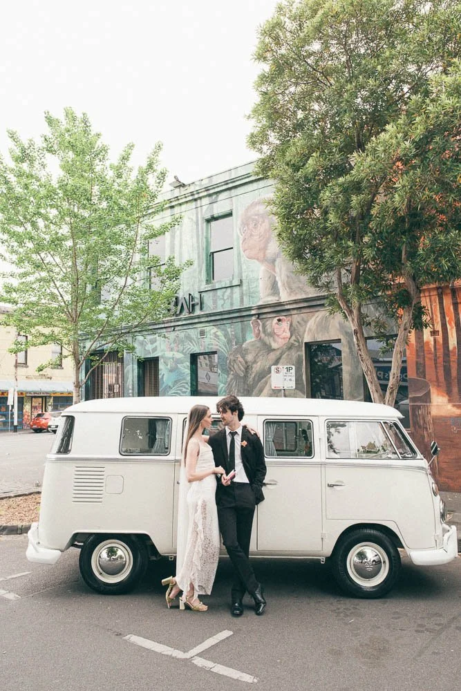 MELBOURNE  EDITORIAL WEDDING PHOTOGRAPHY, BRIDE AND GROOM POSING NEXT TO A OLD SCHOOL VW KOMBI VAN IN FRONT OF HUGE GRAFITTI