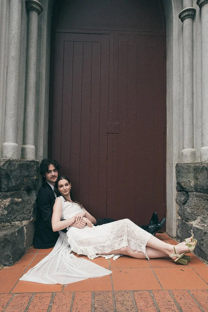 MELBOURNE  EDITORIAL WEDDING PHOTOGRAPHY, BRIDE AND GROOM POSING NEXT TO A CHRUCH DOOR, SITTING ON THE FLOOR