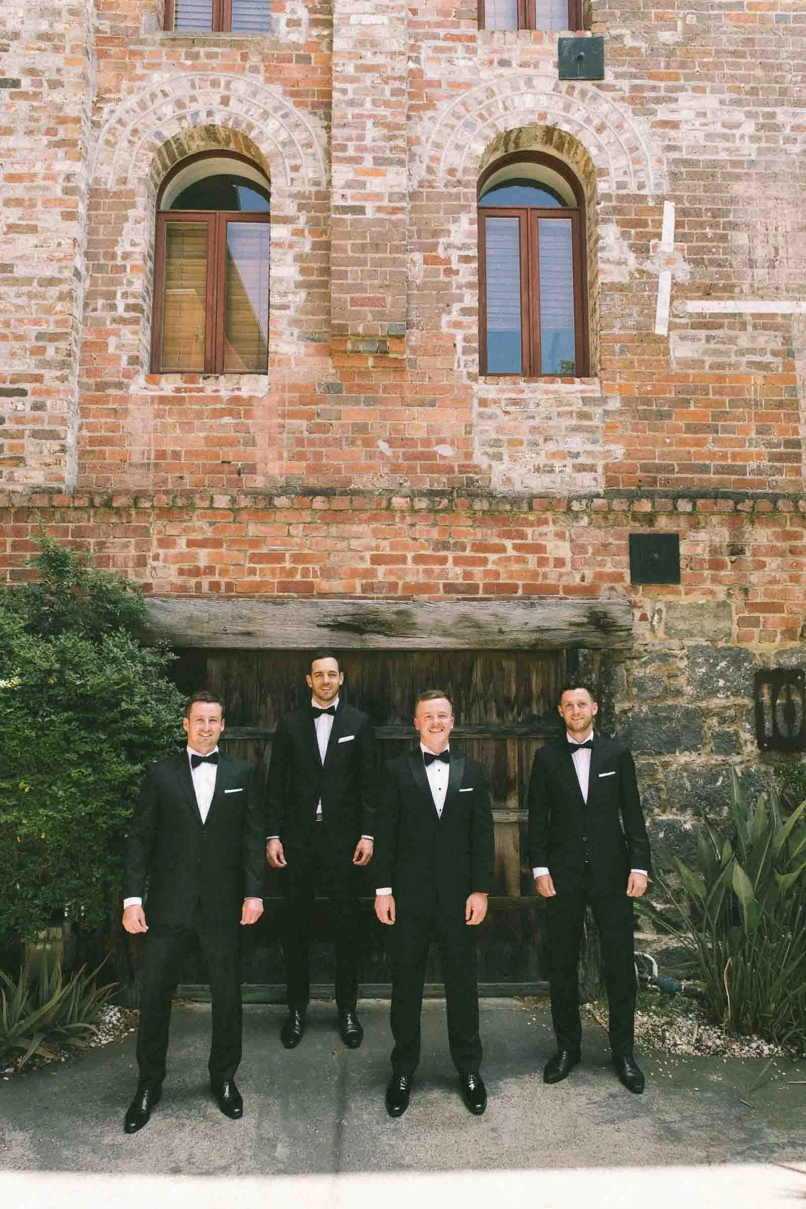 MELBOURNE BOTANICAL GARDEN WEDDING, GROOM GETTING READY, GROOMS PORTRAIT IN A BLACK SUIT ALOONG WITH THE GROOMSMEN