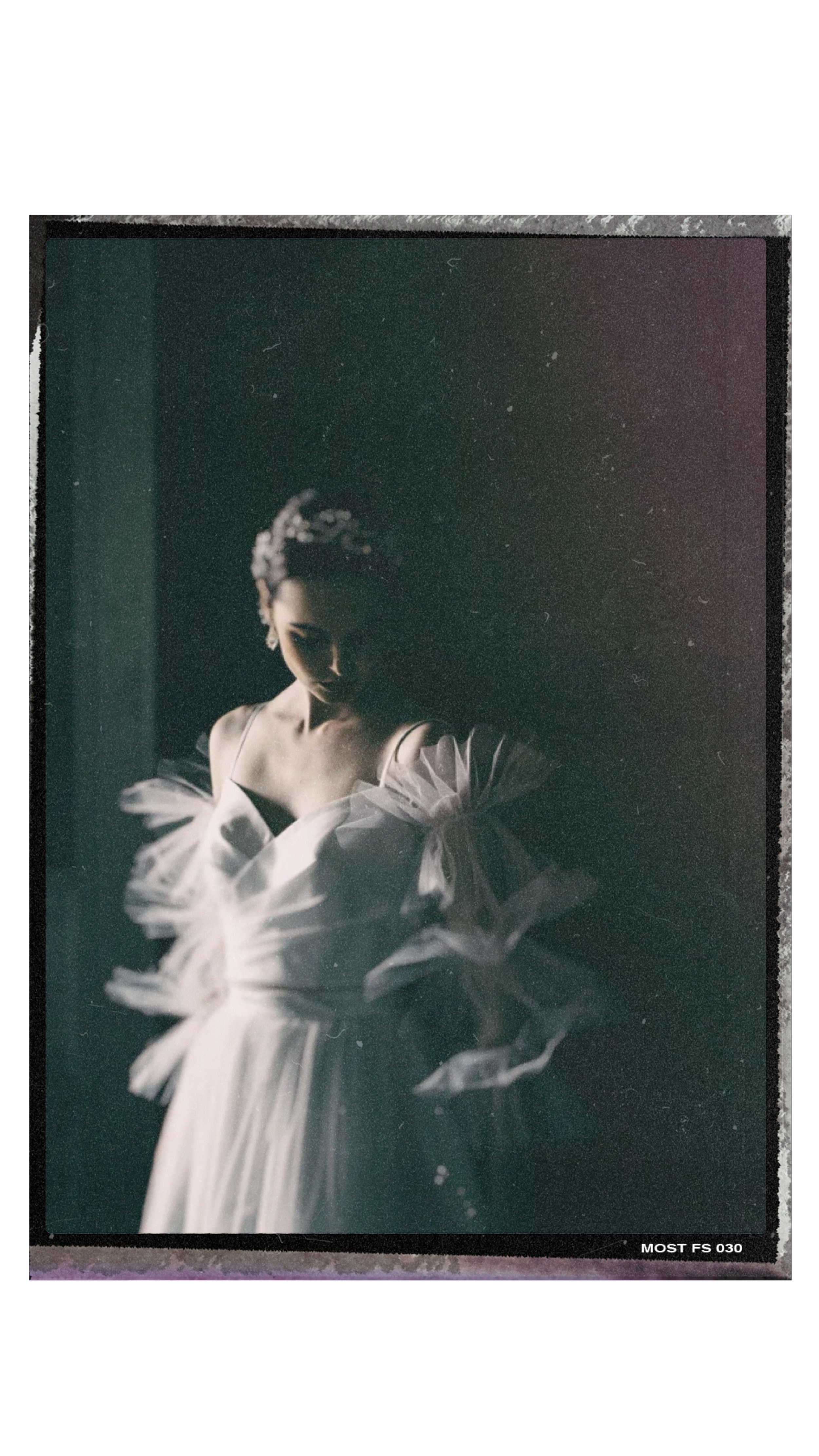 IMAGE OF A MODEL WEARING A WEDDING GOWN PHOTOGRAPHED IN DARK AND MOODY SETTING NEXT TO A WINDOW