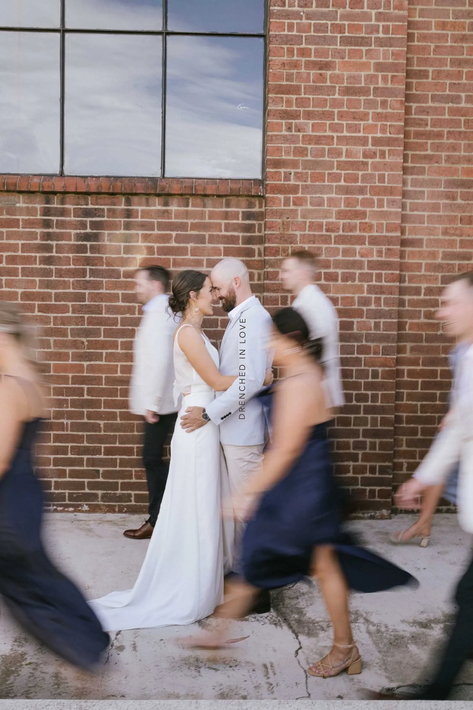 FEDERAL MILLS GEELONG WEDDING WITH COUPLE POSING AND THE BRIDAL PARTY BLURRED WITH SLOW SHUTTER MOVEMENT