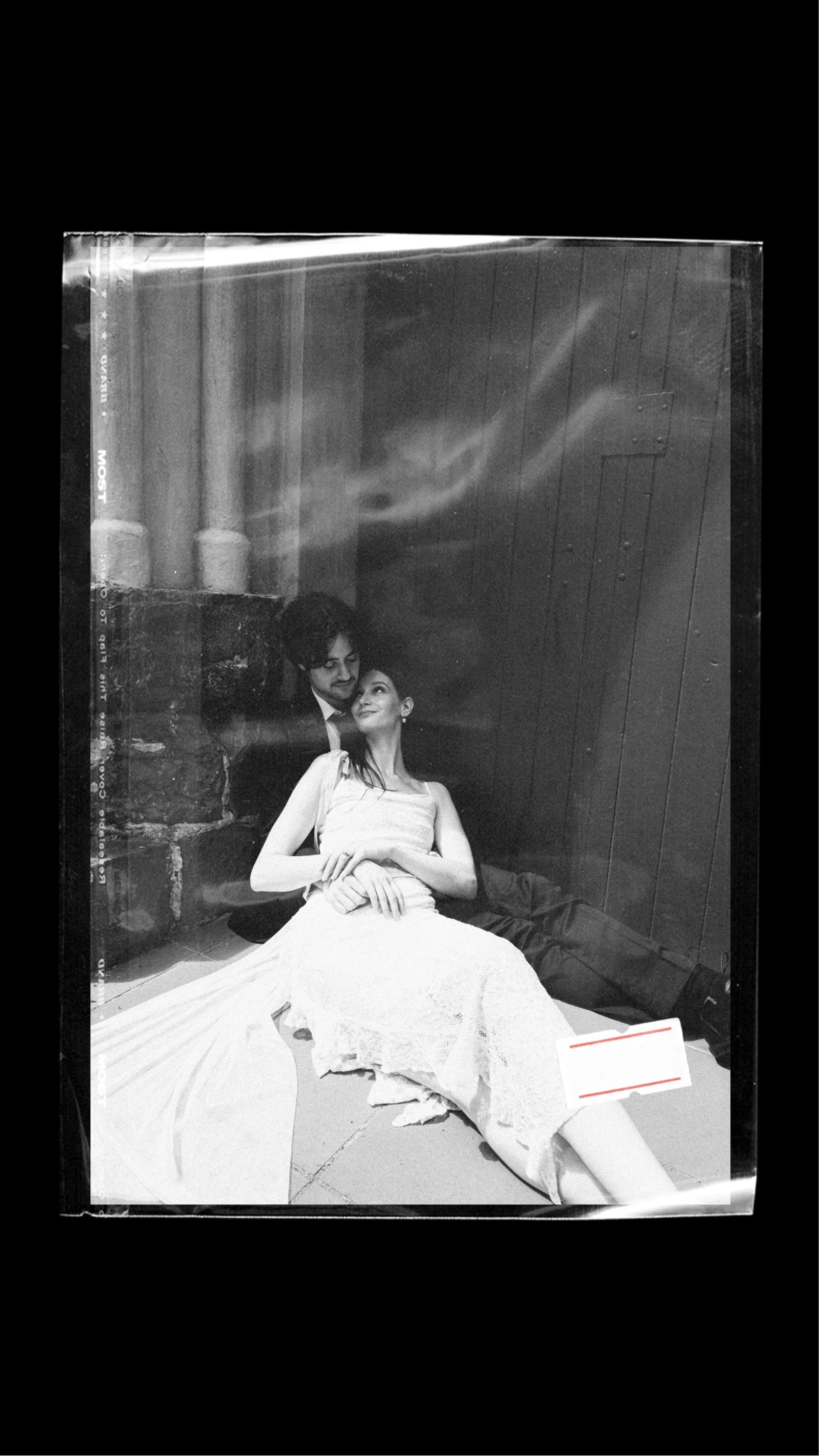 A wedding couple snuggled up on the floor in front of a church