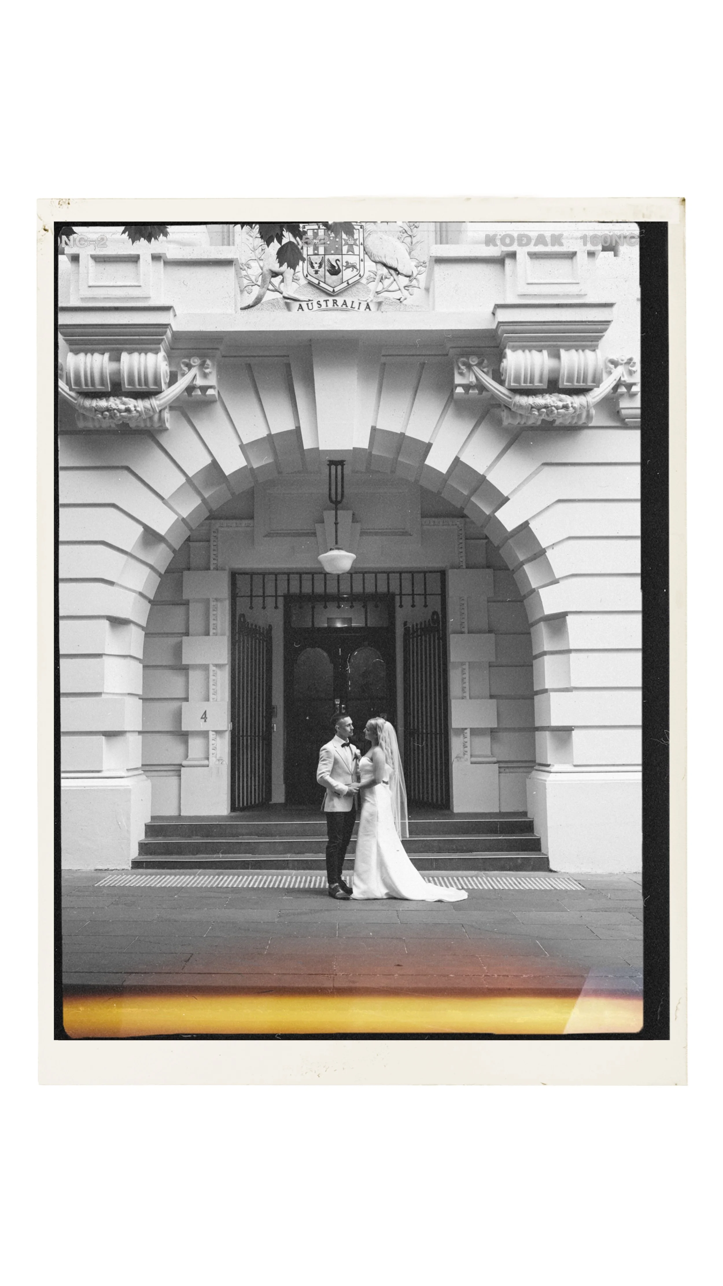 A elopement couple posing in front of the art of the Melbourne Treasury Building, a timeless wedding photo edited in a nostalgic film style way