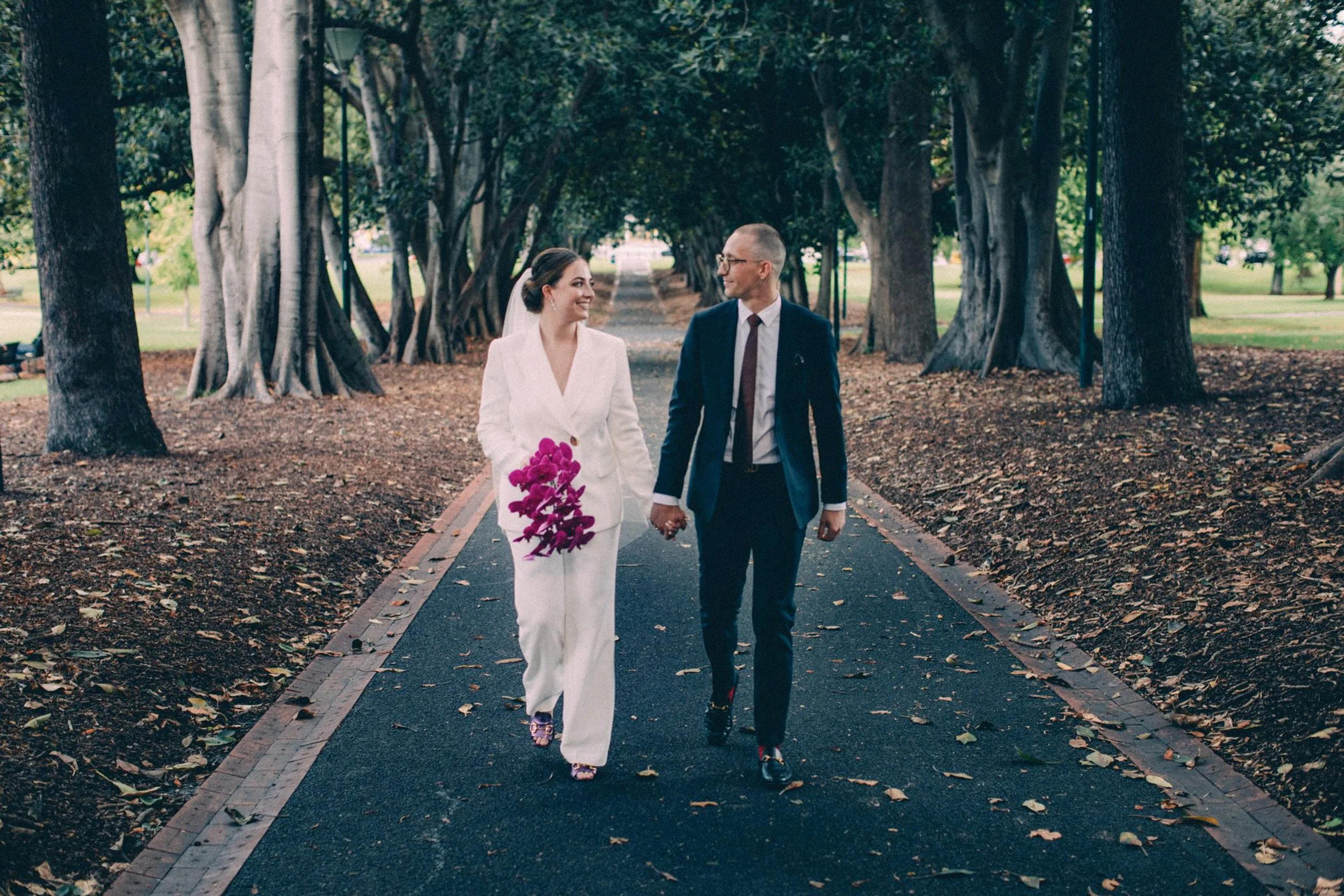 WEDDING COUPLE WALKING THROUGH TREASURY GARDENS IN MELBOURNE