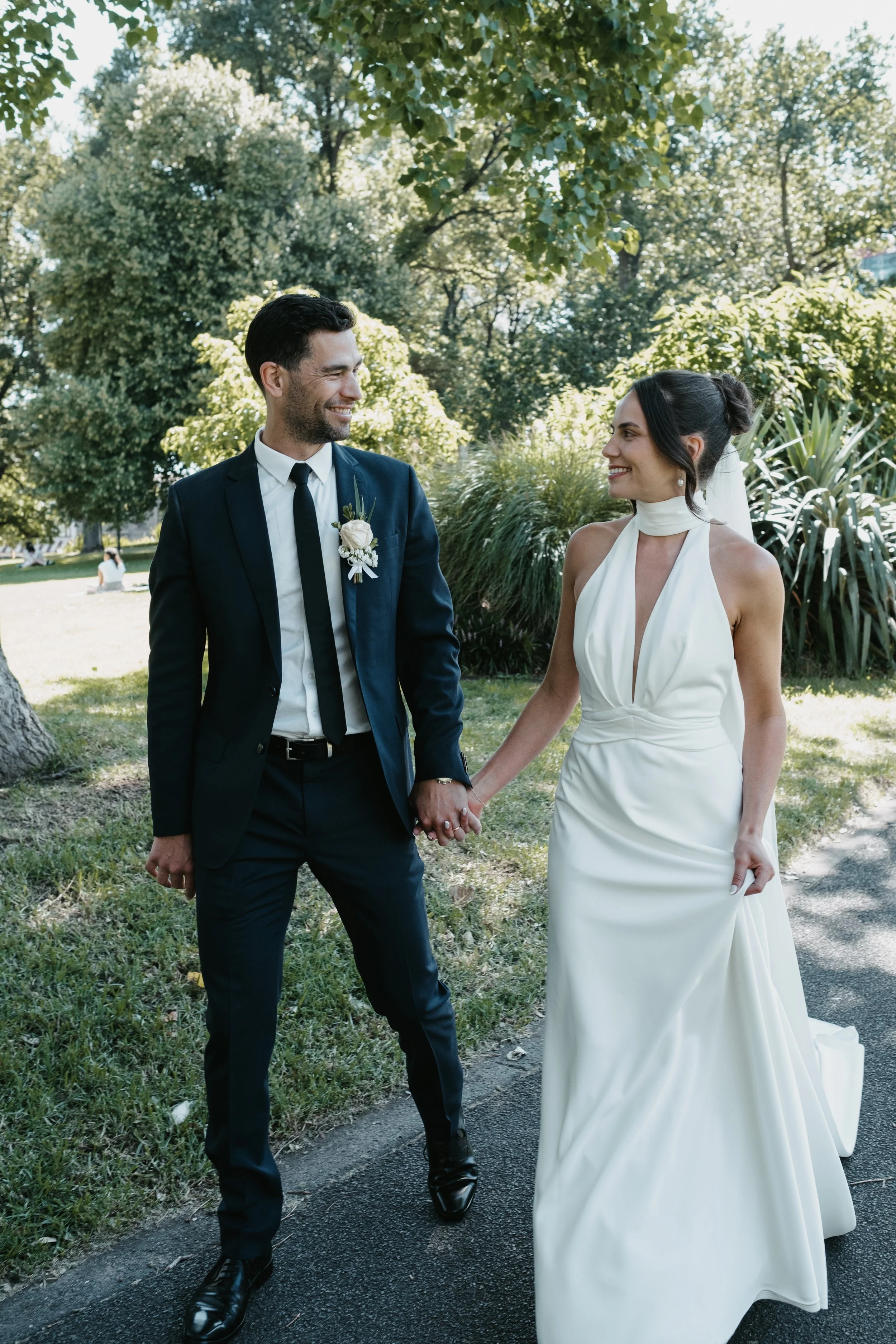 Bride and groom holding hands walking in a park