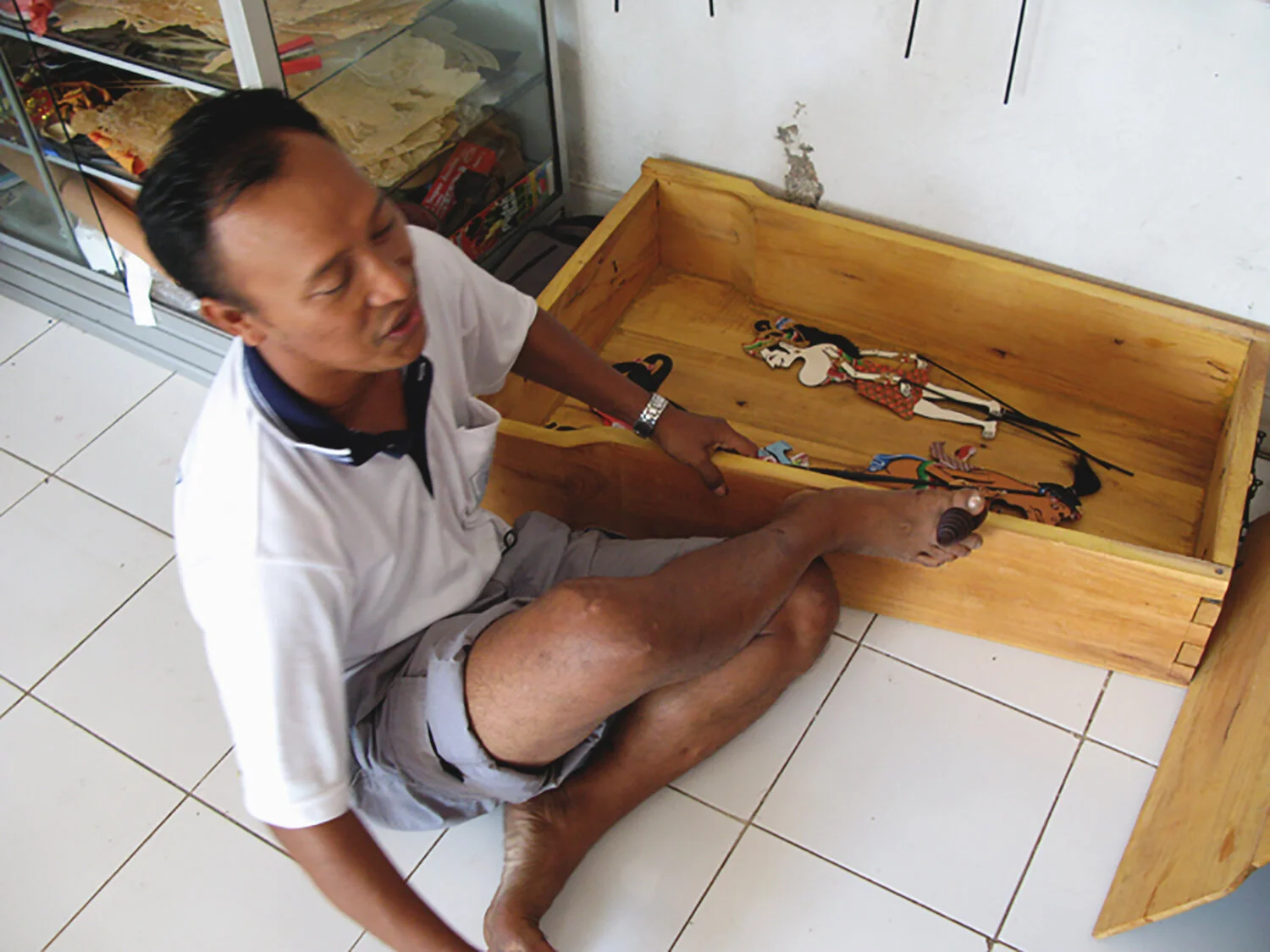Traditional way that knocking sounds are used with a metal object knocked on a box with the foot is being demonstrated
