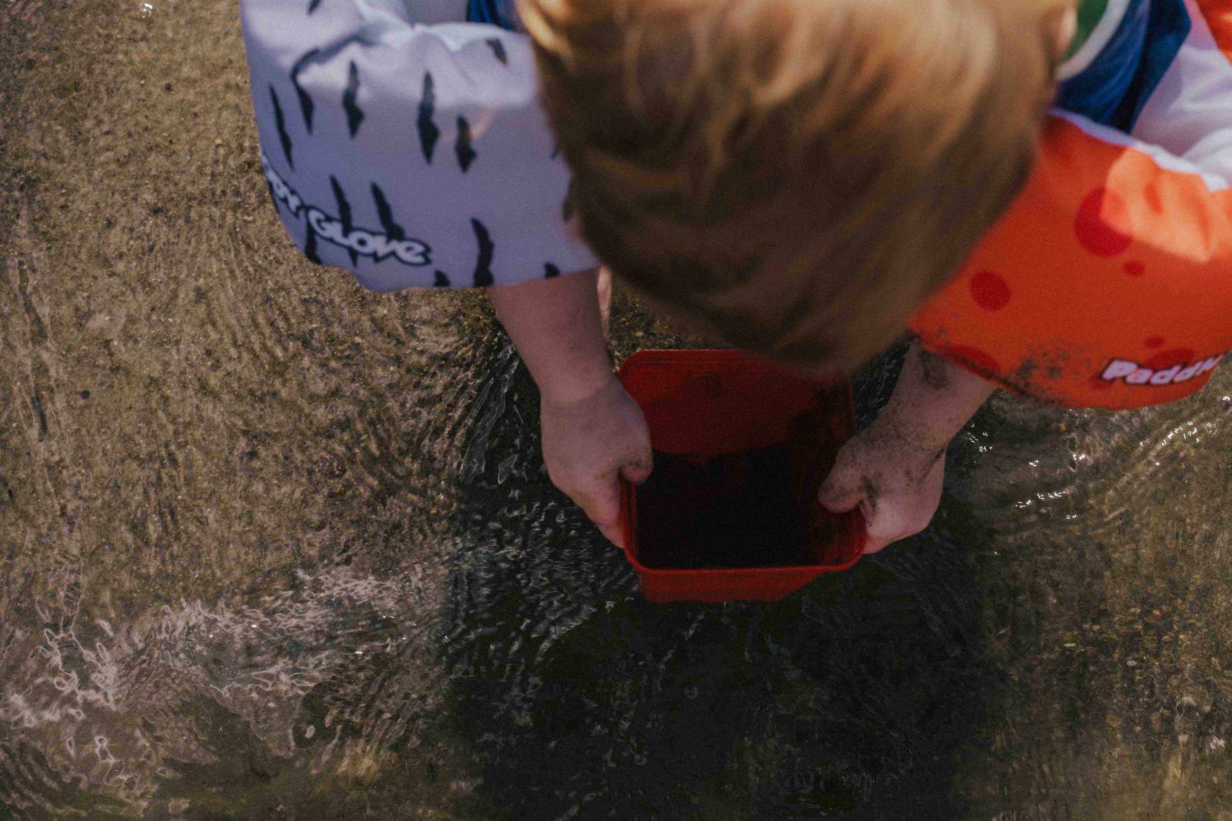Candid image of a boy exploring and playing in water, capturing the magic of childhood during a Forever Ago Photography session in Jerome Michigan