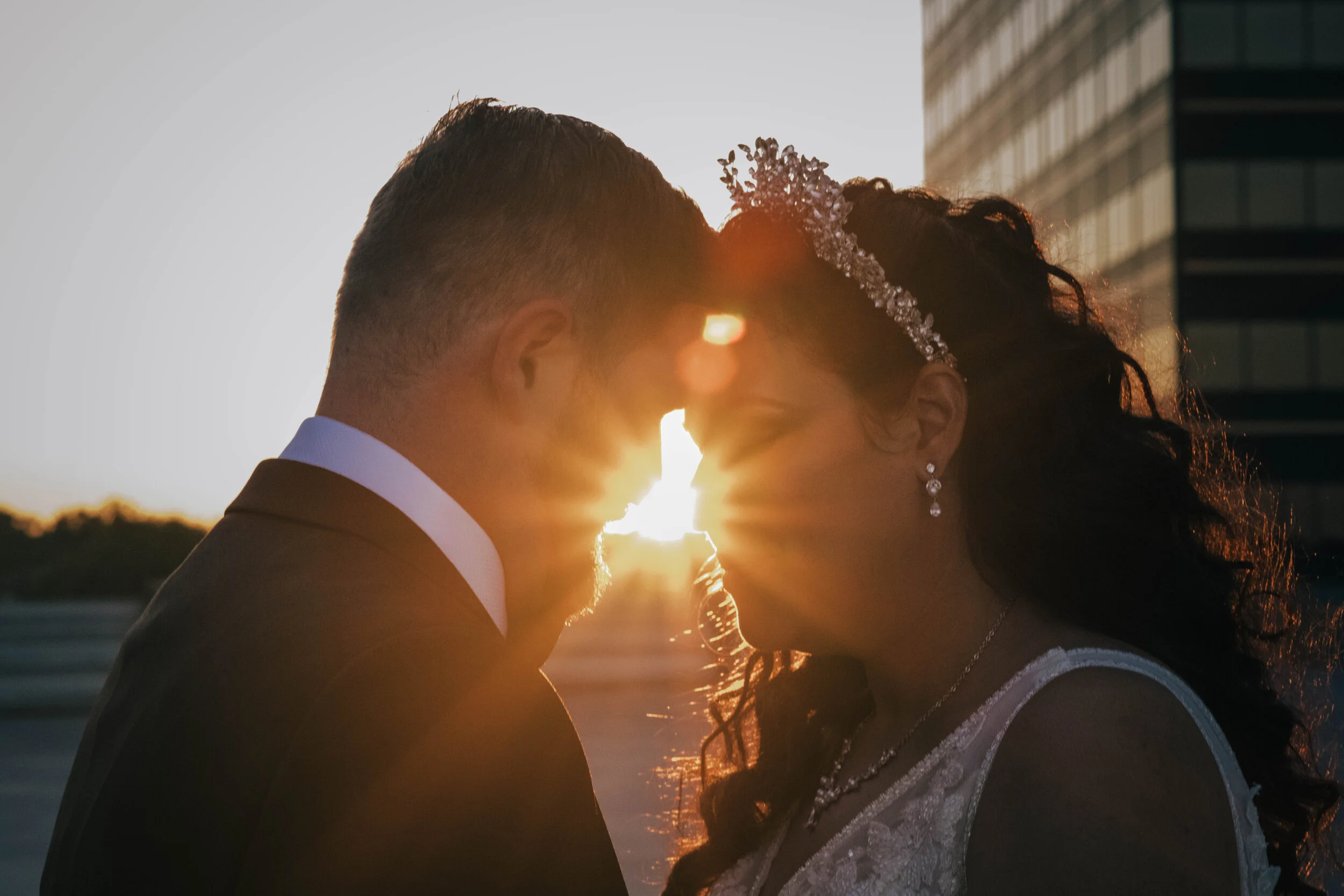 Candid moment of a bride and groom sharing a kiss as the sun sets, bathed in golden hour light during a wedding photography session by Forever Ago Photography in Detroit Michigan