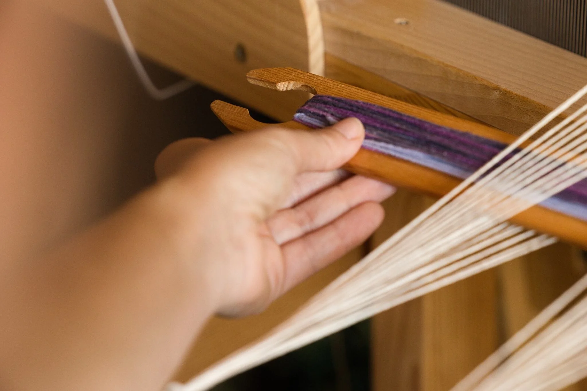 Detailní fotografie rukou u tkalcovského stavu určené pro facebook stránky tkalcovství ve Vyškově