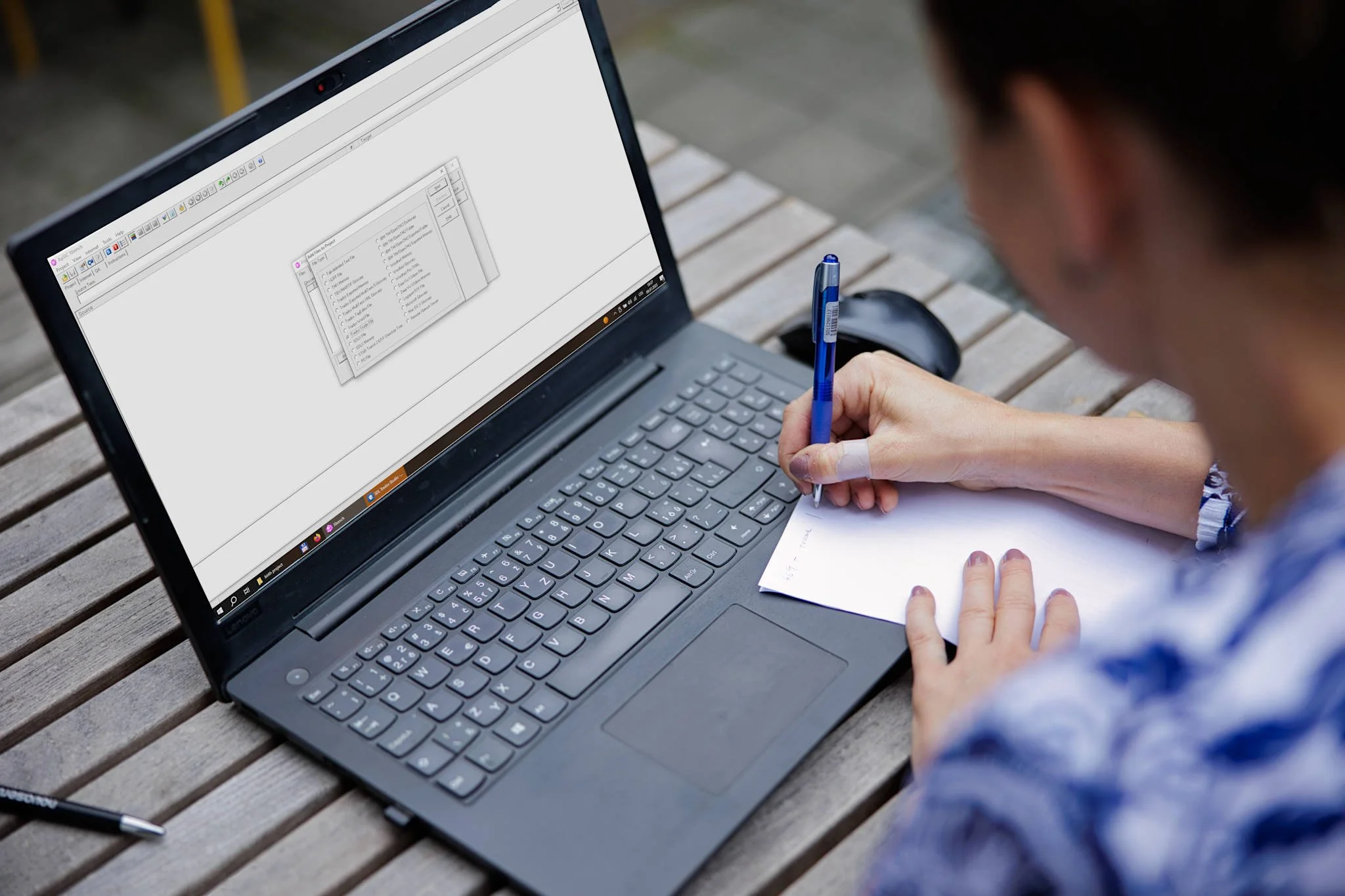 fotografie rukou u zapnutého nootebooku, přes rameno osoby.