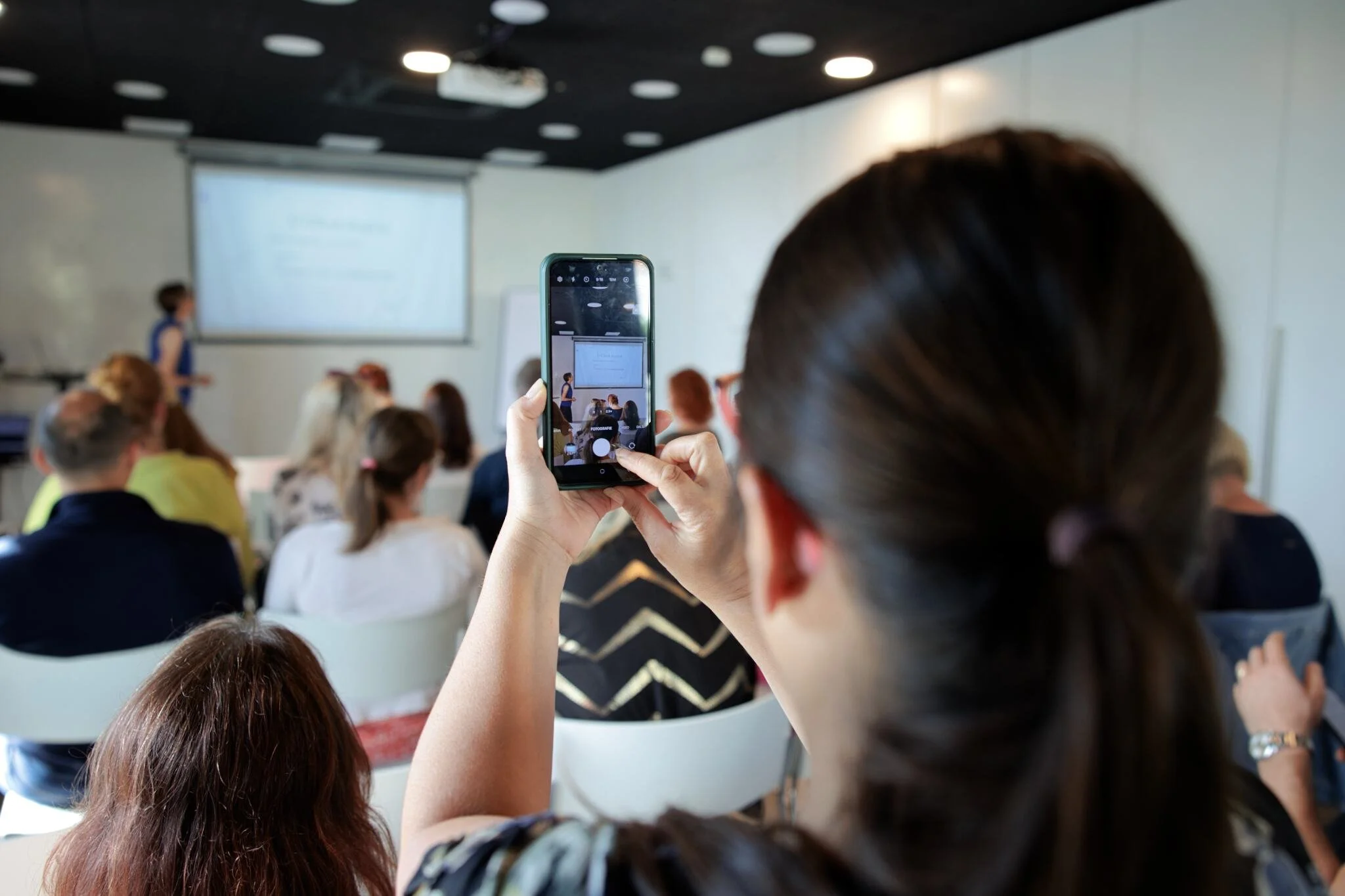 účastník si fotí konferenci na mobilní telefon