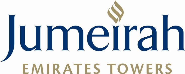Jumeirah Emirates Towers logo with the text in blue and gold, featuring a stylized gold flame or torch symbol above the letter 'm' in 'Jumeirah.'