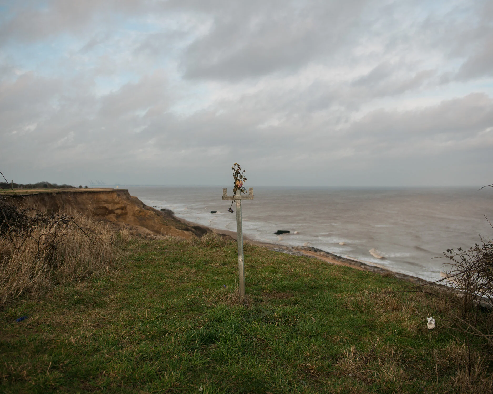 The last remaining railing of the steps that used to lead down to the beach near Hopton, Suffolk, memorialised with plastic flowers.