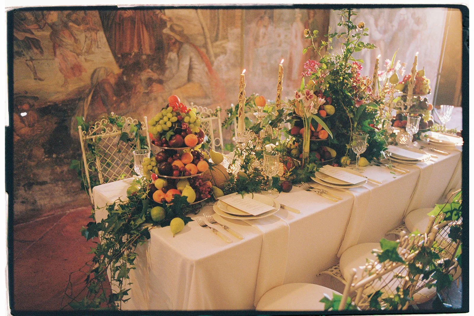 Artful reception table with flowers, fruit, and candles.