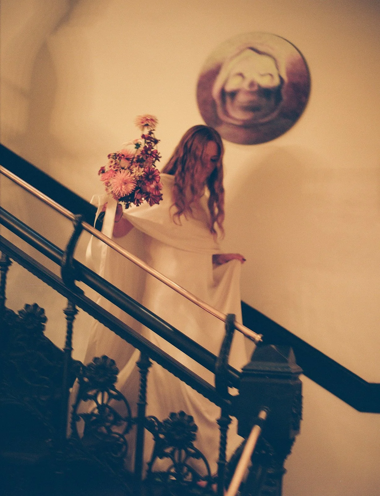 Bride carrying a bouquet of flowers down a staircase