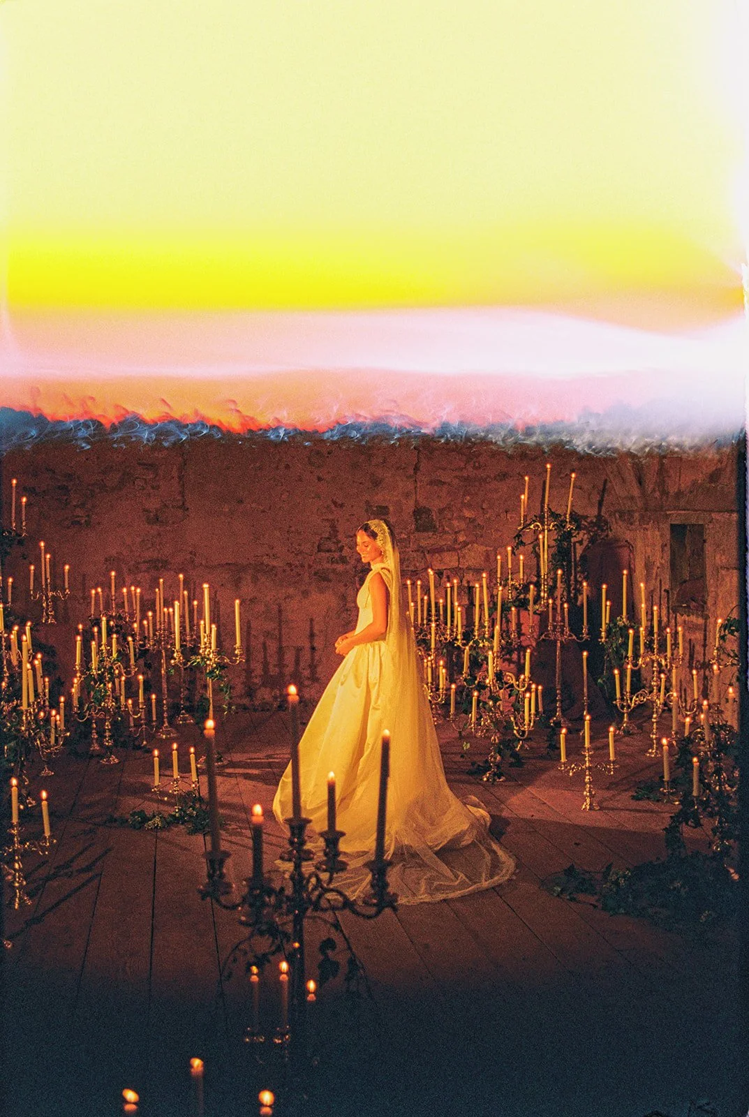 Bride standing among candlelit floral arrangements