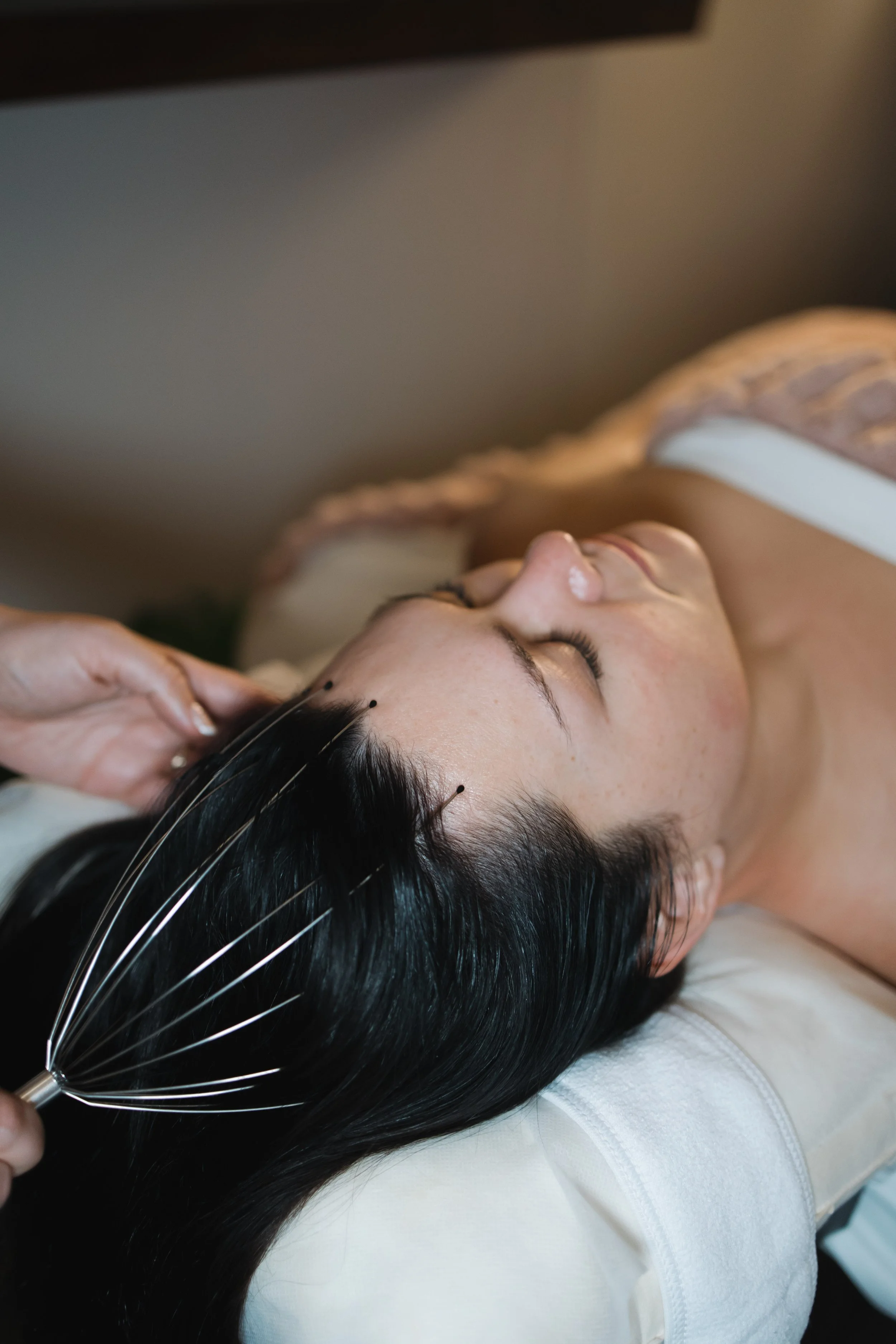 A woman receiving a scalp massage with esthetician Lauren at Face and Forme Aesthetics