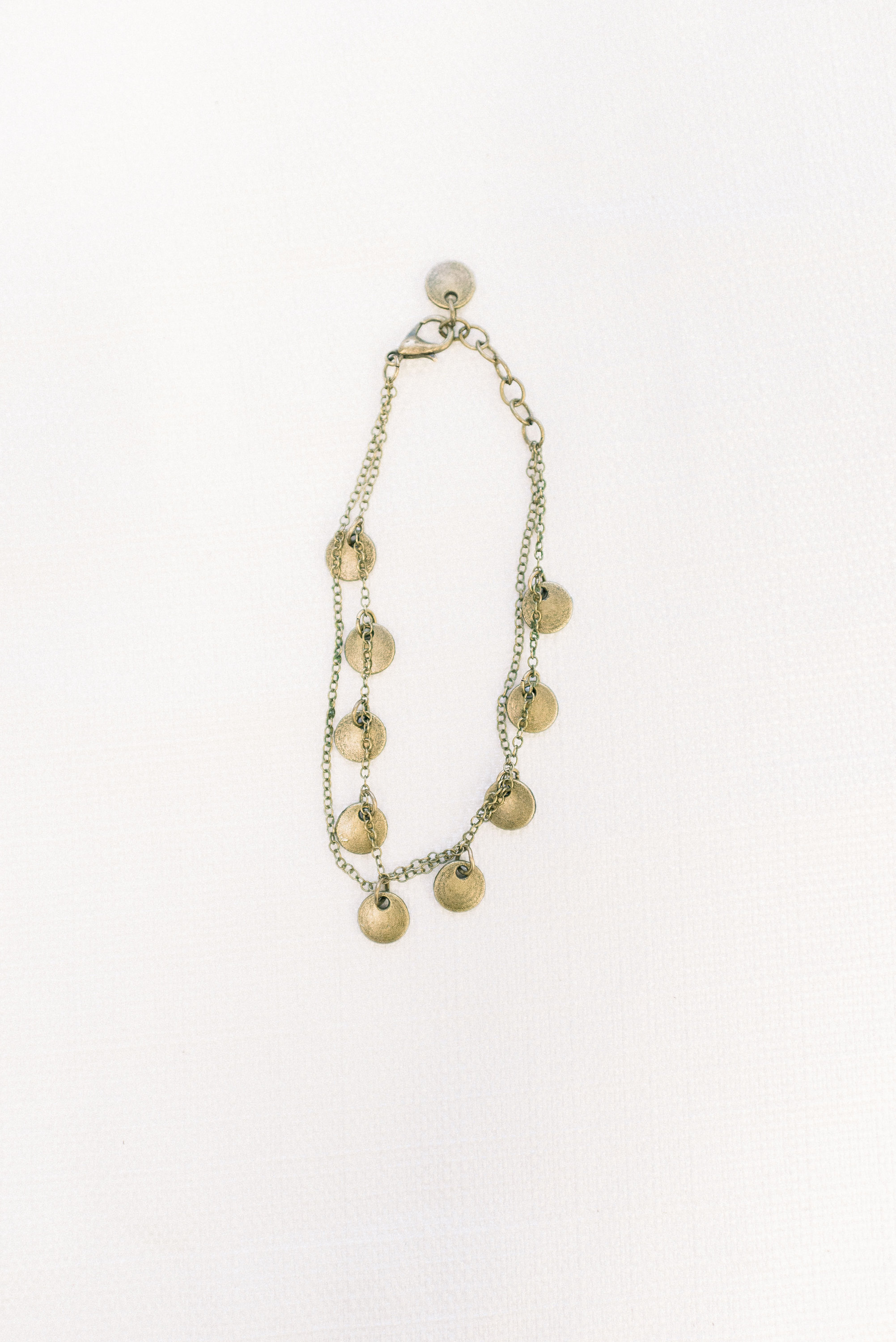 double layered delicate bronze chain bracelet with 9 small bronze circle pendants hanging from chain.