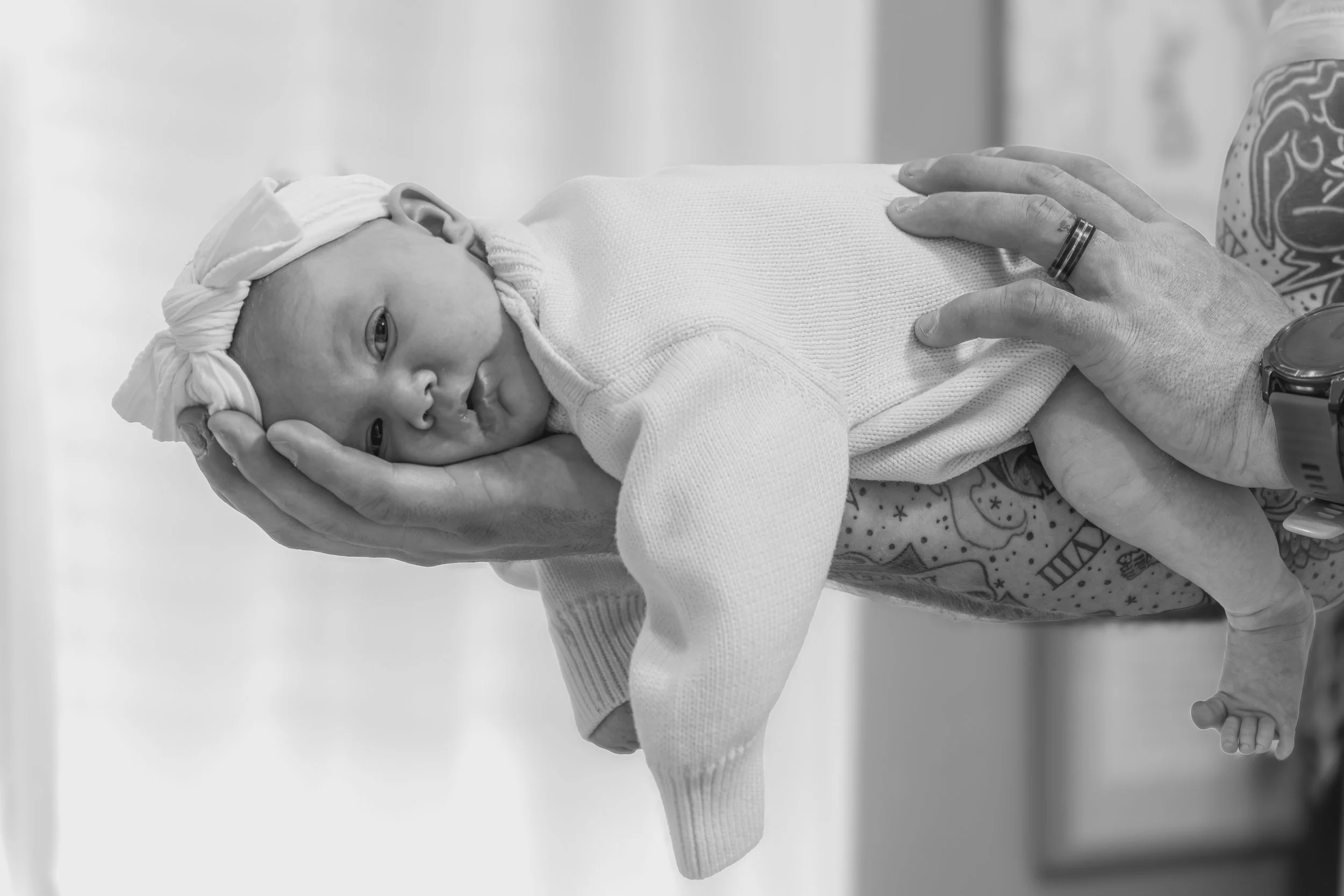 A happy family with a father, mother, and newborn baby on a bed in a cozy bedroom.