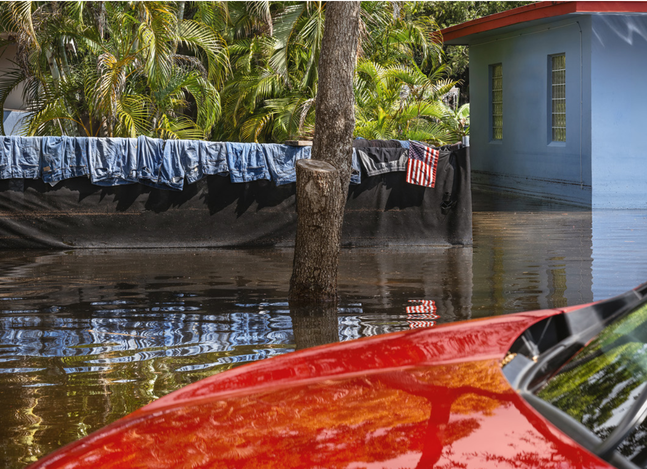 Anastasia Samoylova photograph Aesthetica Vamika Sinha. Red car in front of flooding and American flag and jeans