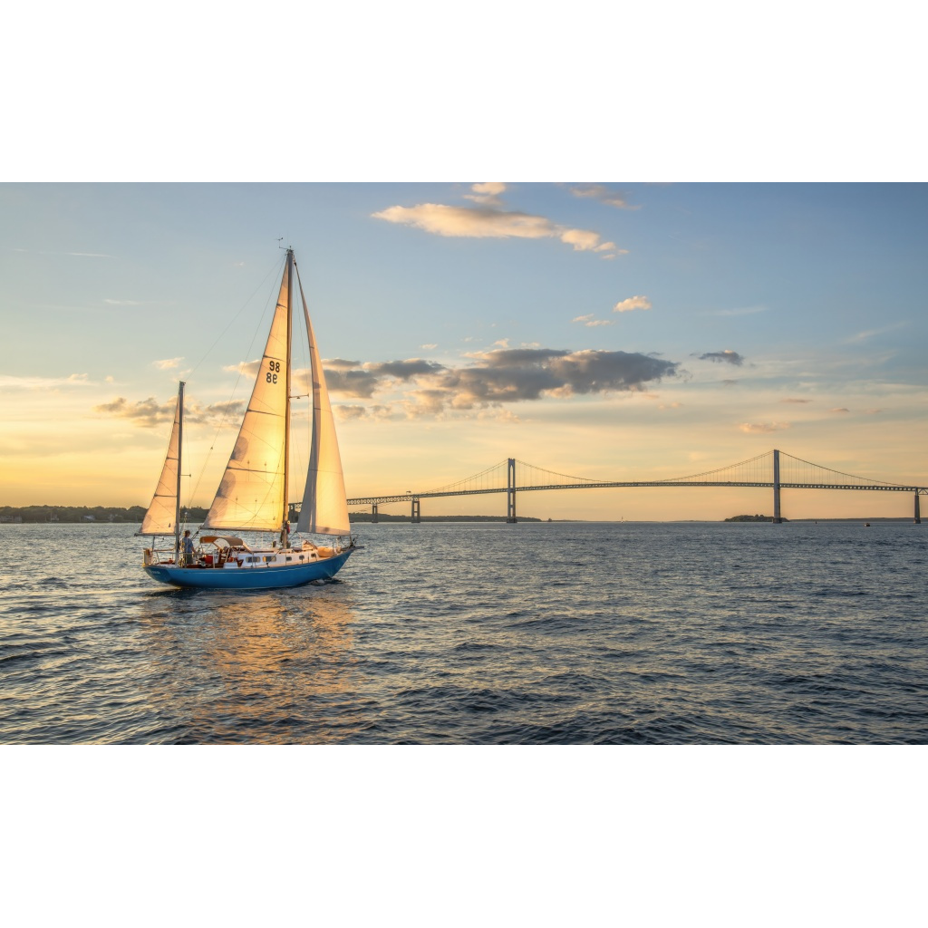 Sailboat sailing at sunset on Narragansett Bay with the Newport Pell Bridge in the background