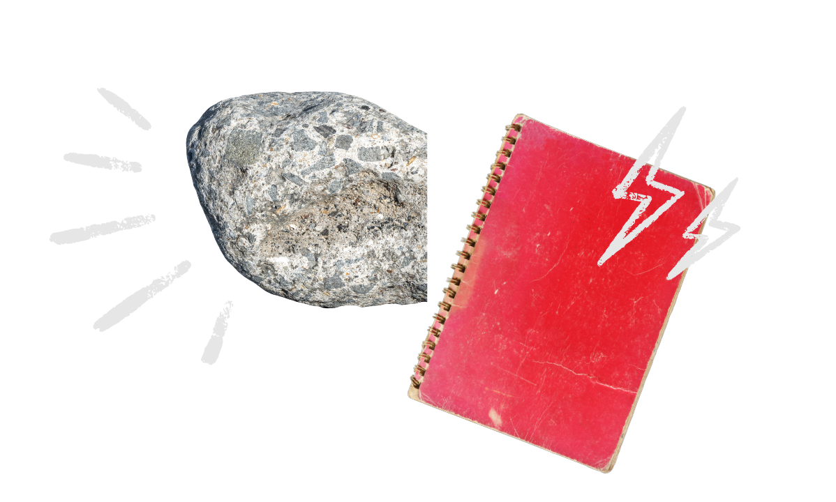 A large gray rock and a red spiral notebook with white lightning bolt designs on the cover are placed on a black background.