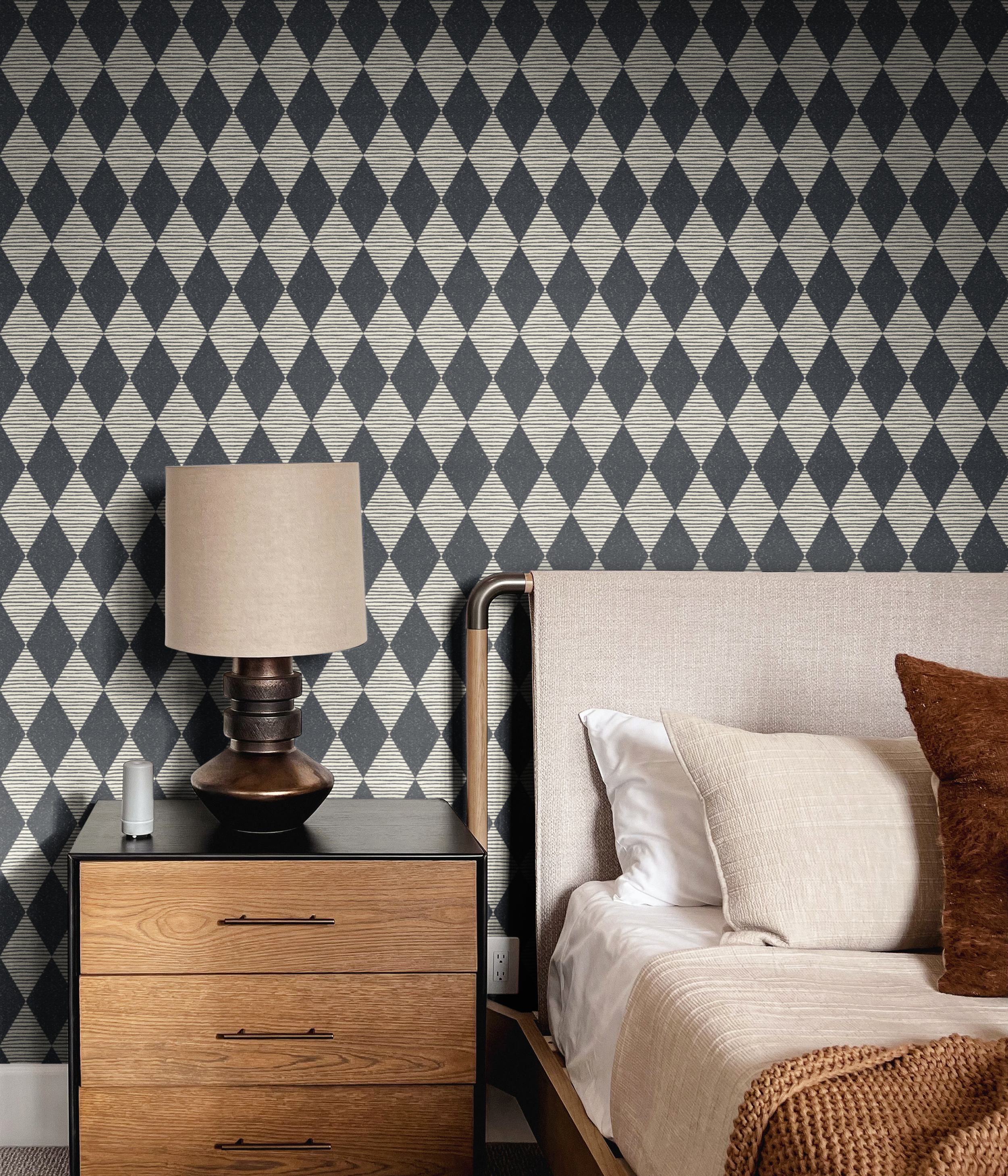 Navy black and cream harlequin diamond wallpaper in a styled bedroom with wood nightstand