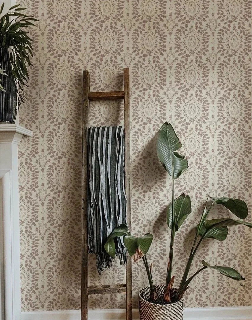 Damask pattern wallpaper in cream and taupe, styled with a wooden ladder and striped throw blanket