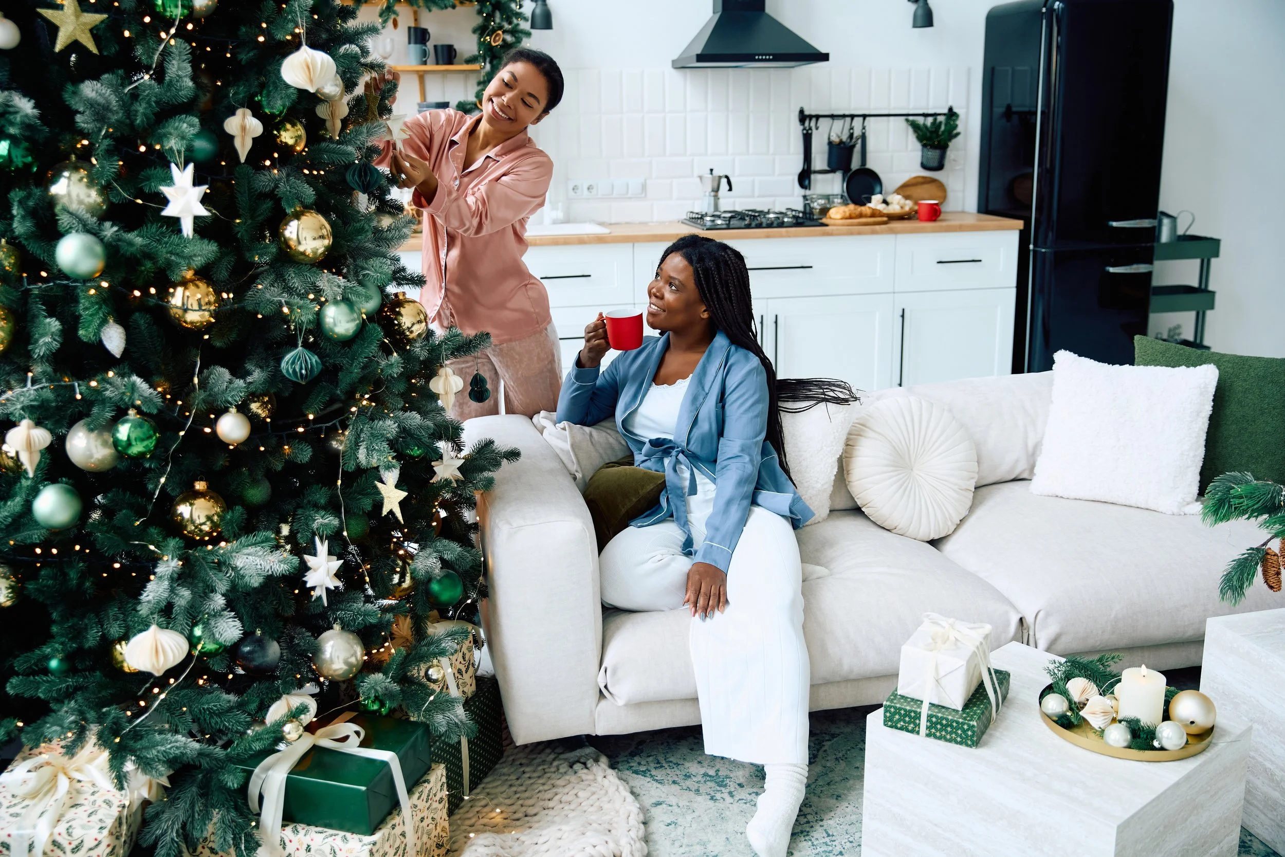 woman-decorates-christmas-tree-while-friend-drinks-2026-01-08-02-12-20-utc.jpg