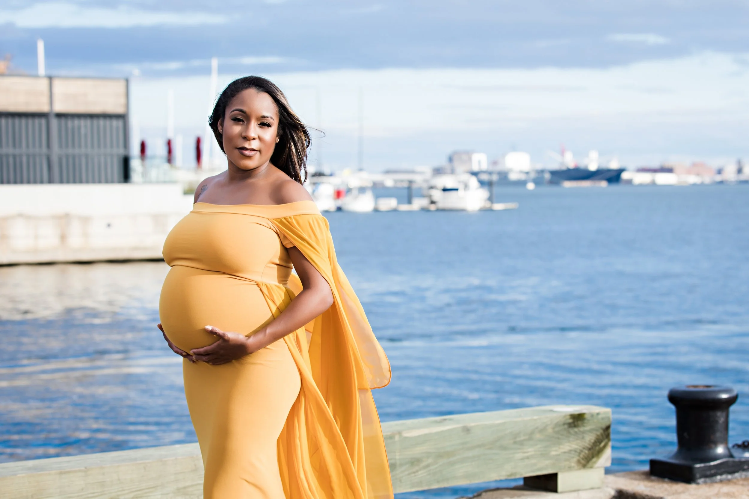 Pregnant woman in yellow dress by waterfront