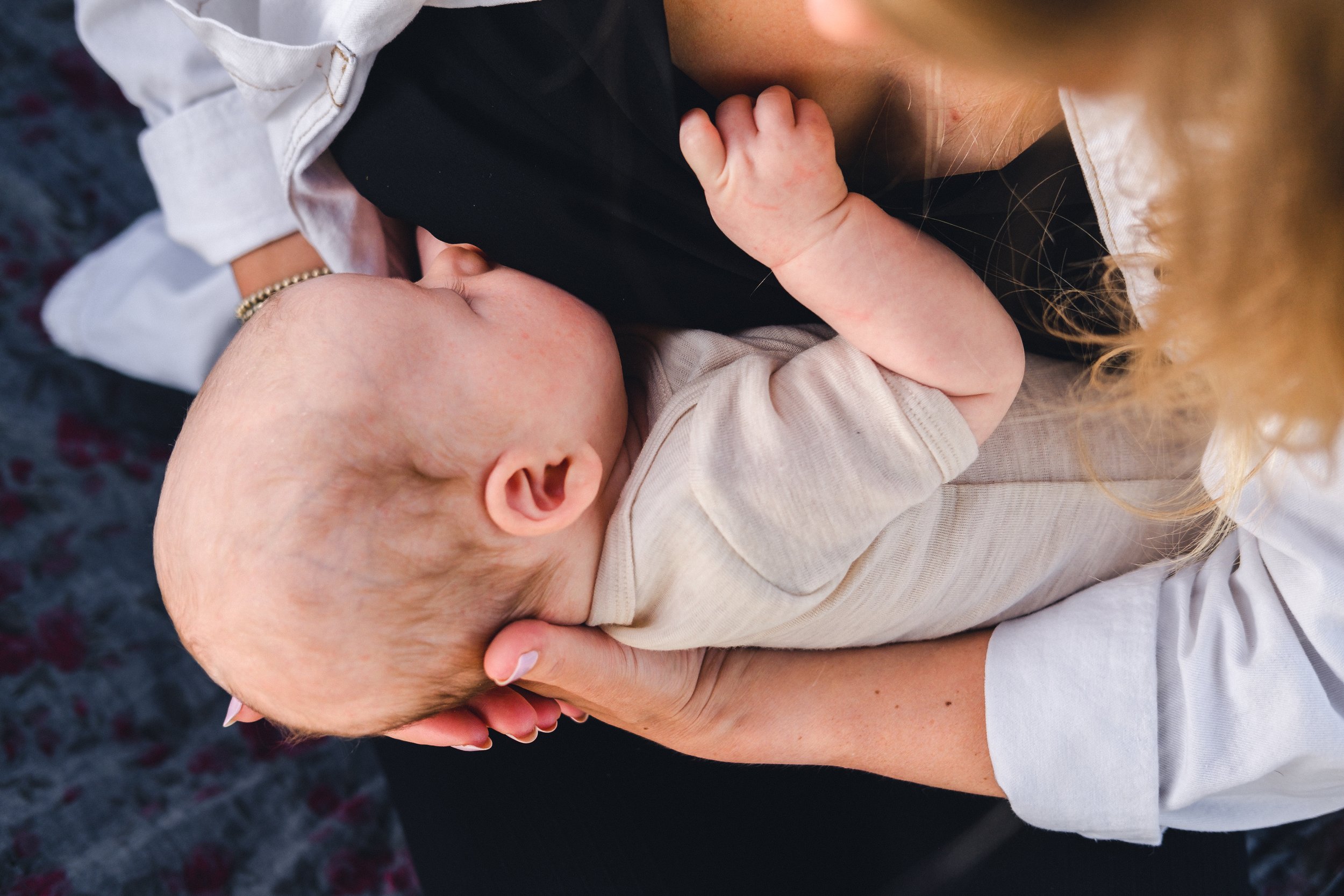 a close up shot from above a blonde lady of her breastfeeding her baby