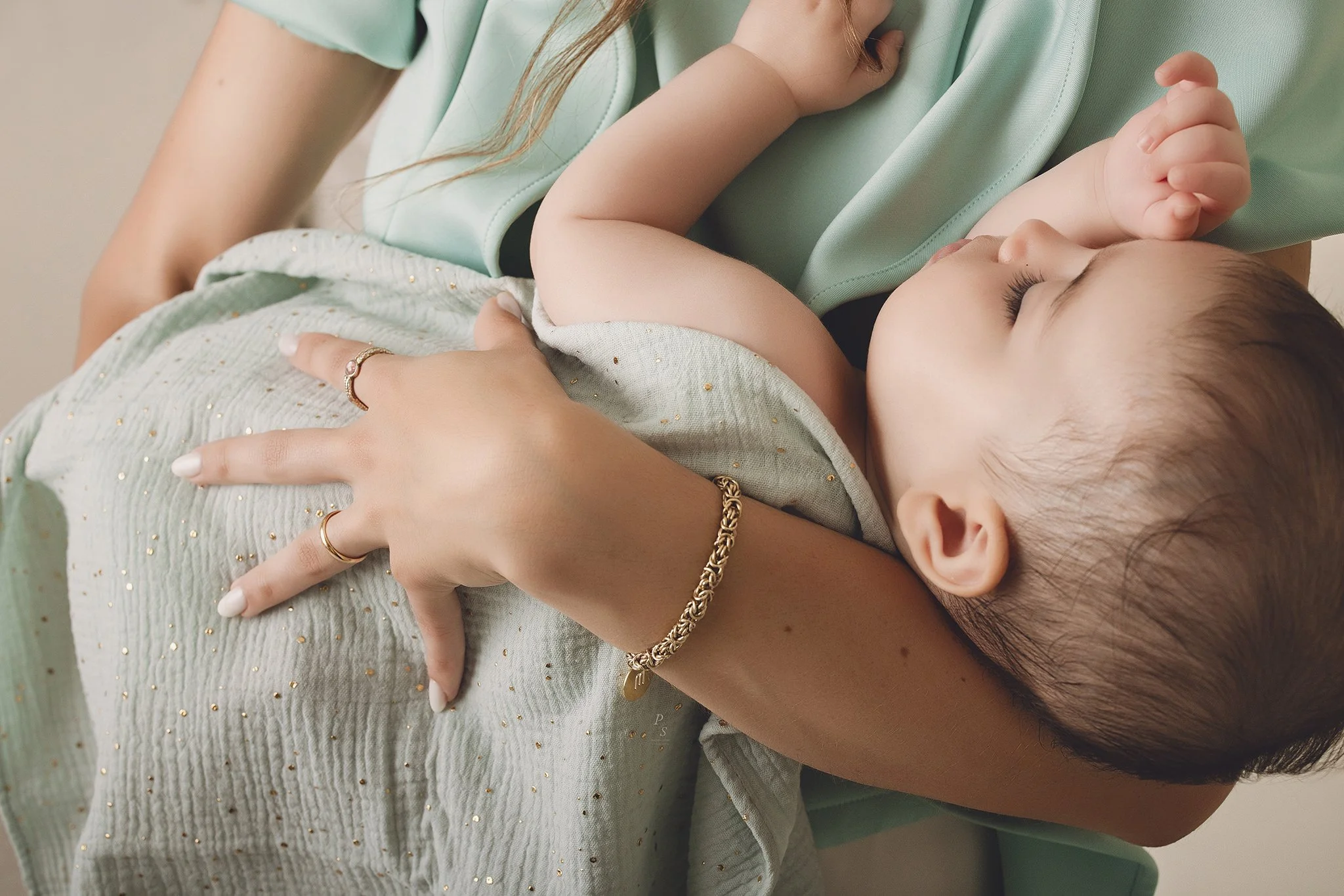 bebé a dormir ao colo da mãe, ambas usando roupas em tons de verde.  sessão fotográfica em estúdio no Porto