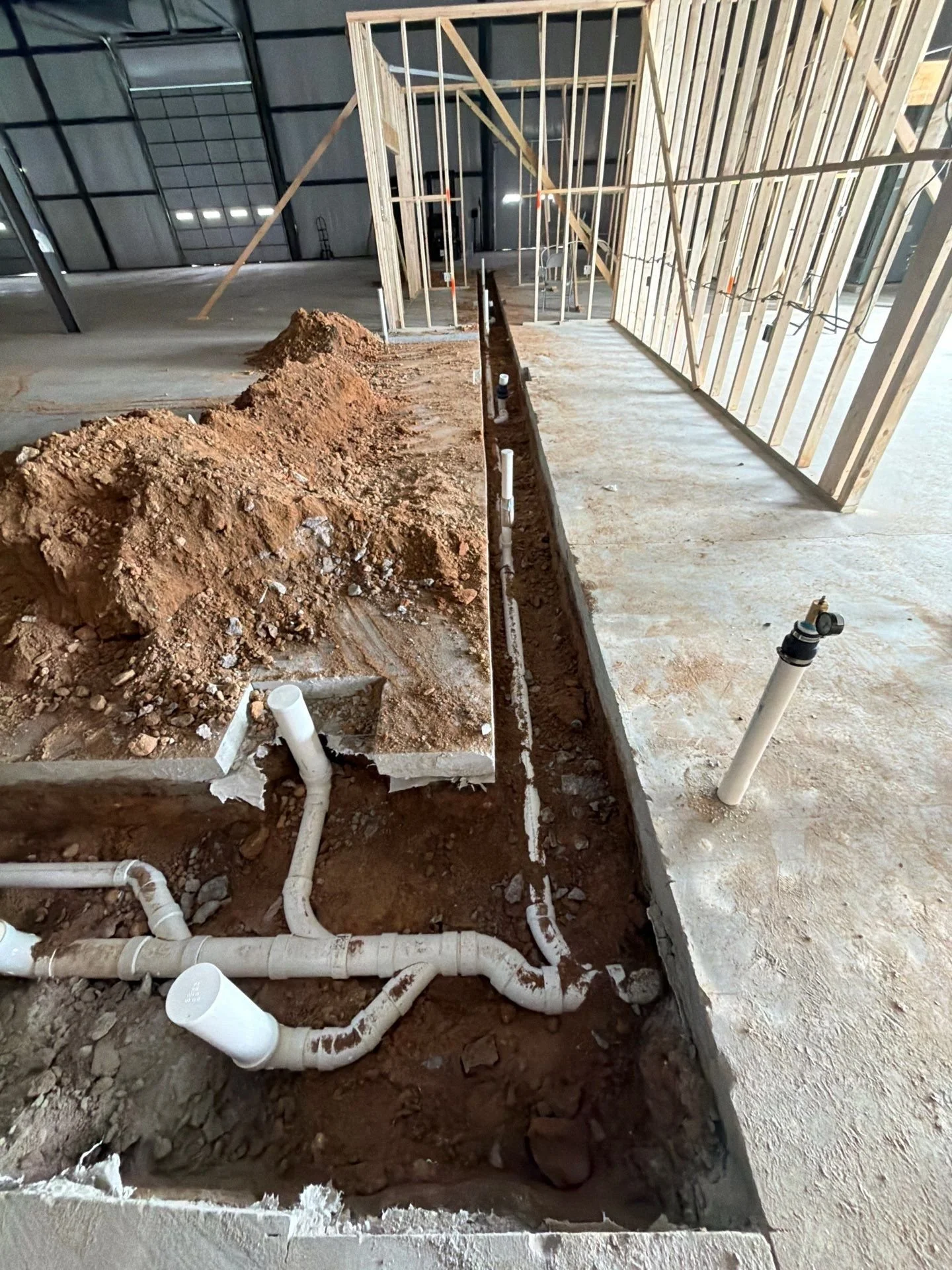 Construction site with exposed plumbing pipes and framing for walls in a building under construction.