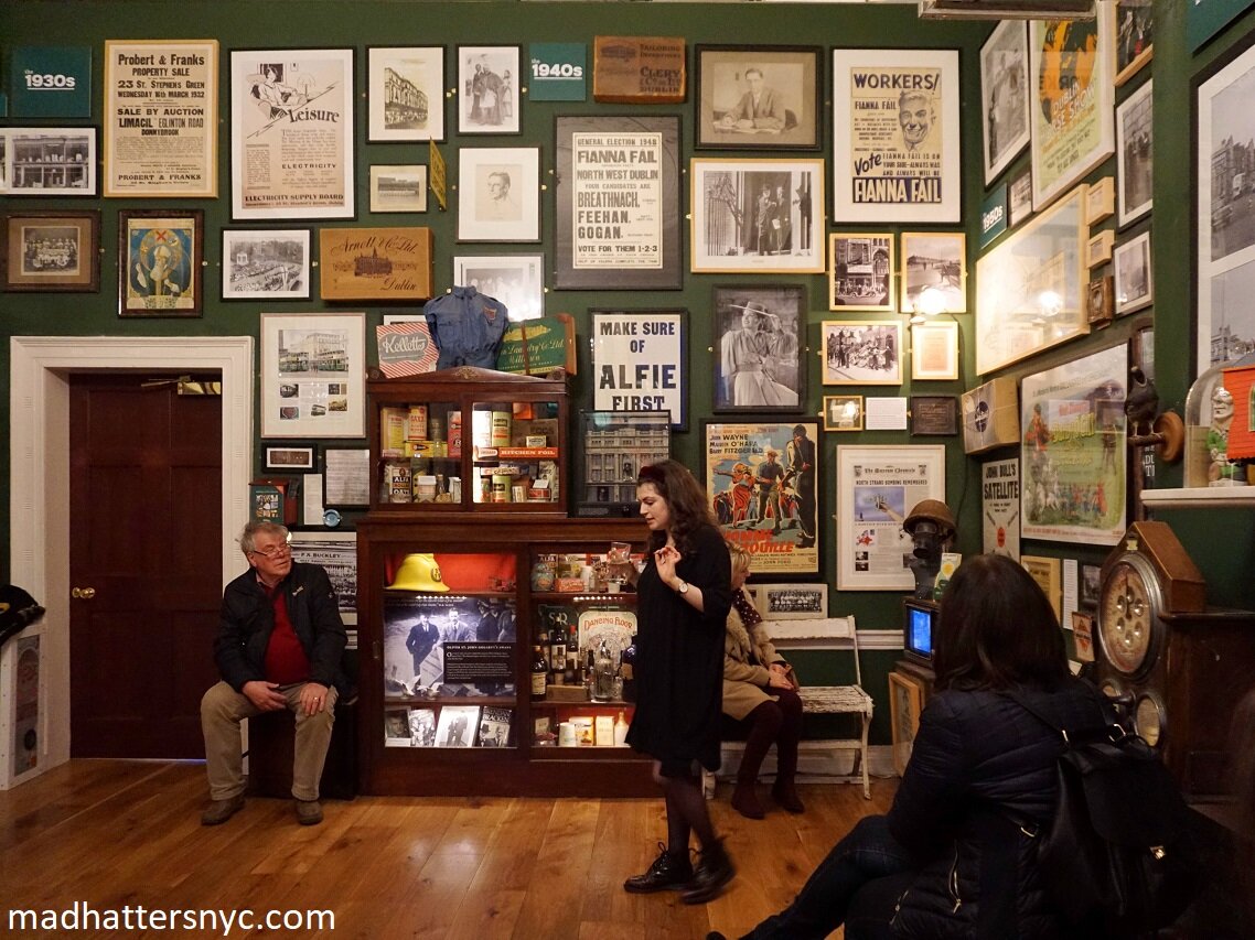 Tour guide in The Little Museum of Dublin with walls covered in historical artifacts organized by decade