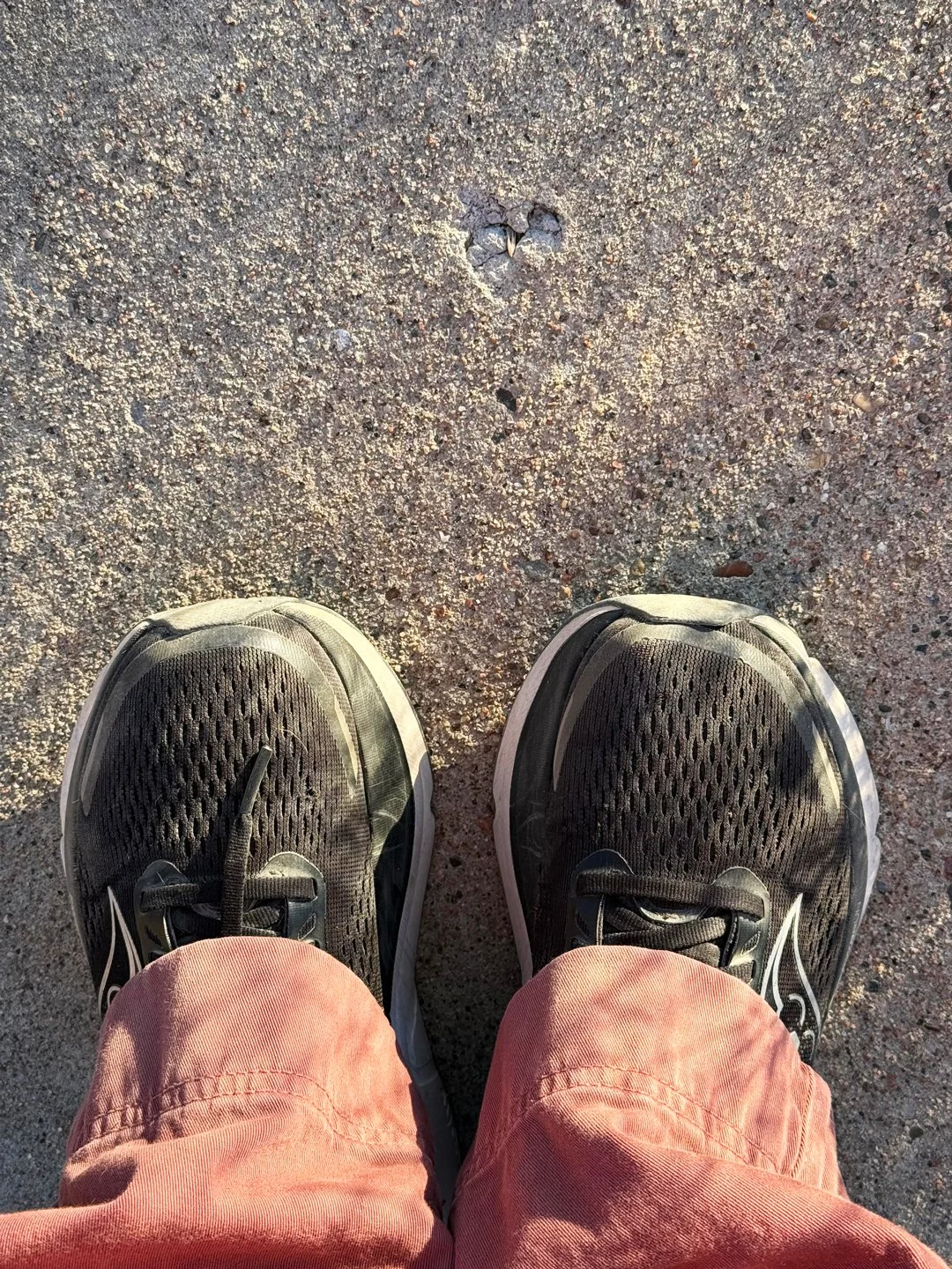 Sun and shadows cascade over a sidewalk heart and my red pants.