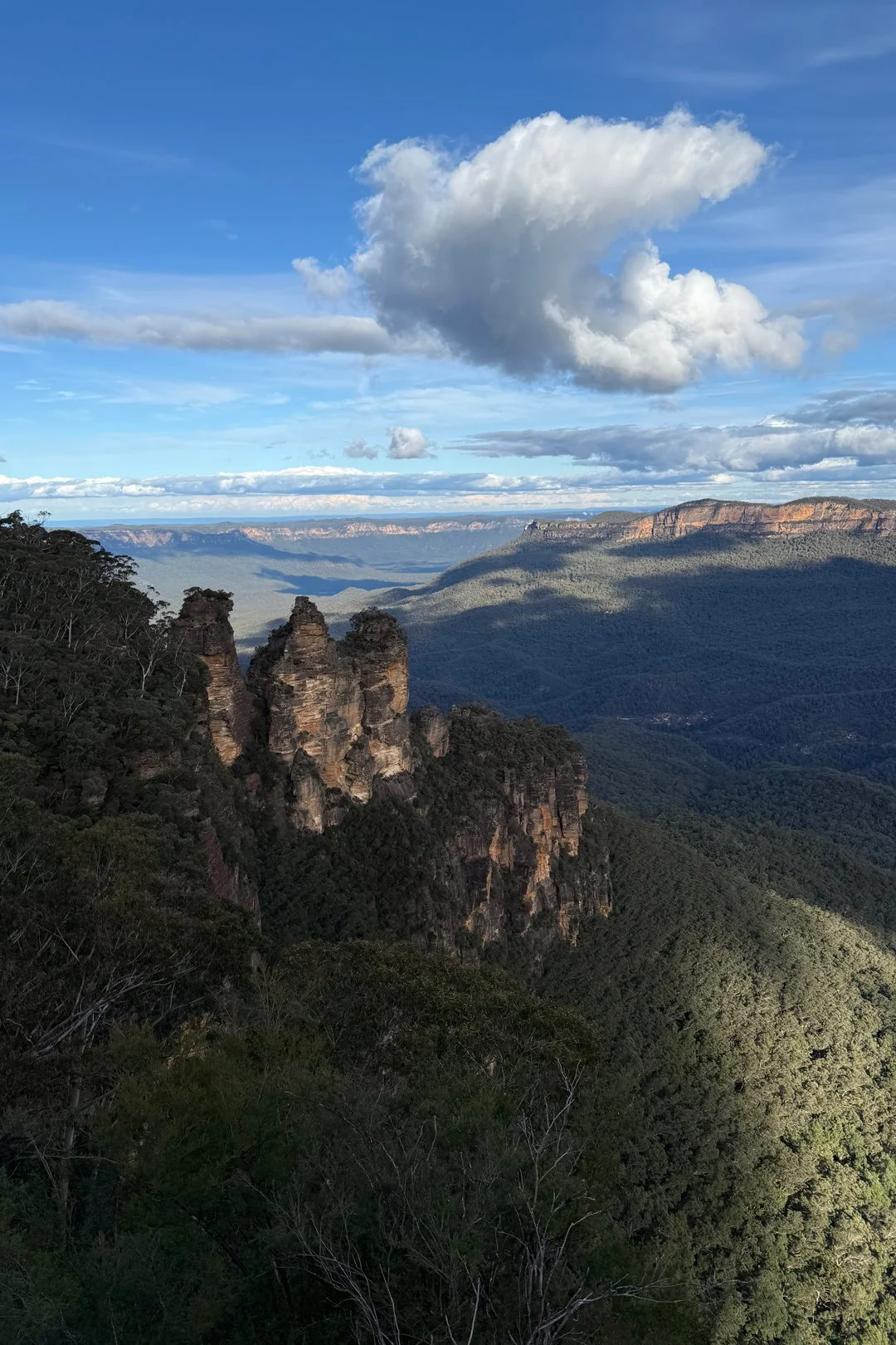 A sideways heart-shaped cloud hovers above the Three Sisters rock formation in the Blue Mountains.